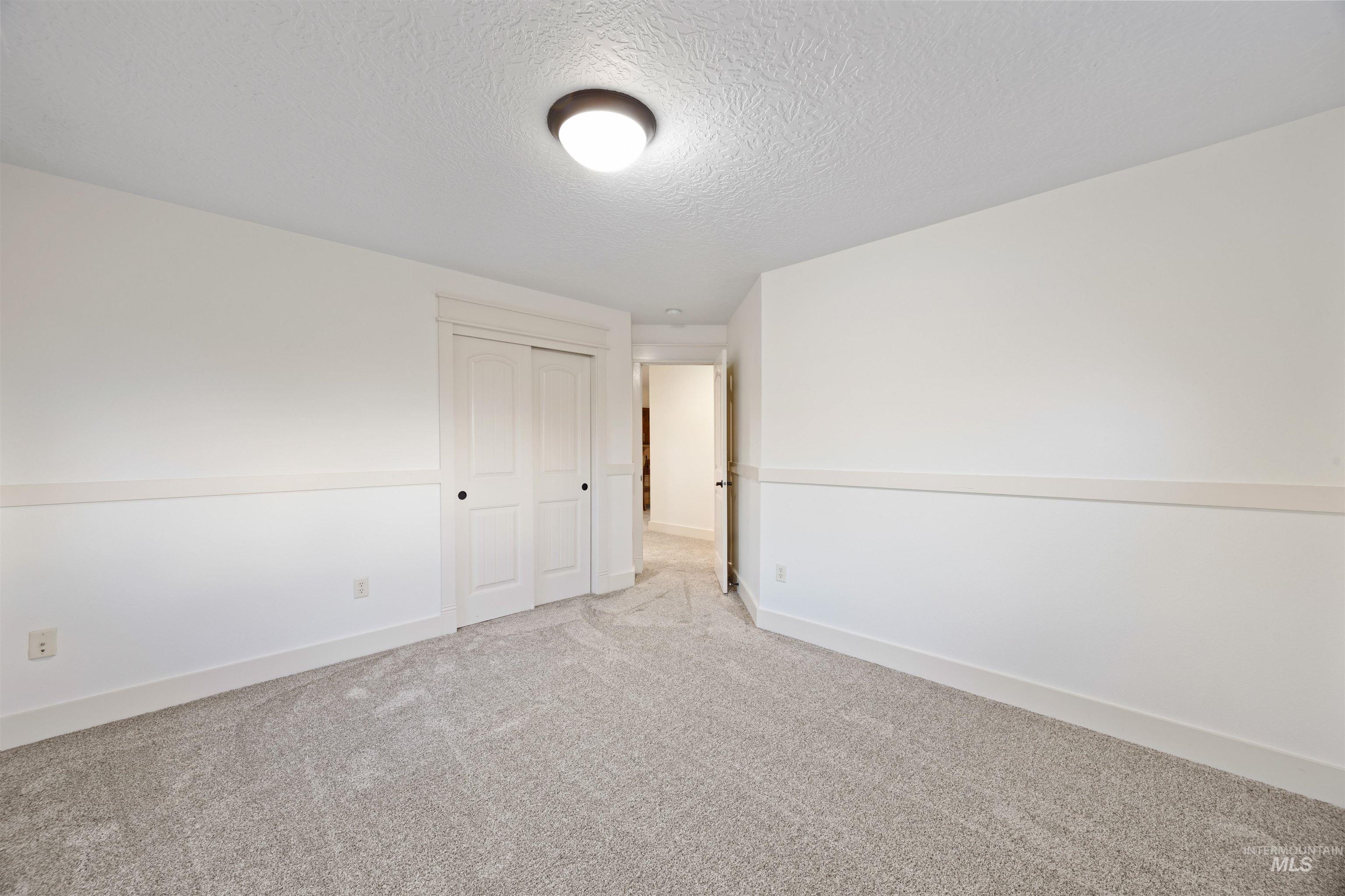 Empty room with a textured ceiling and carpet floors