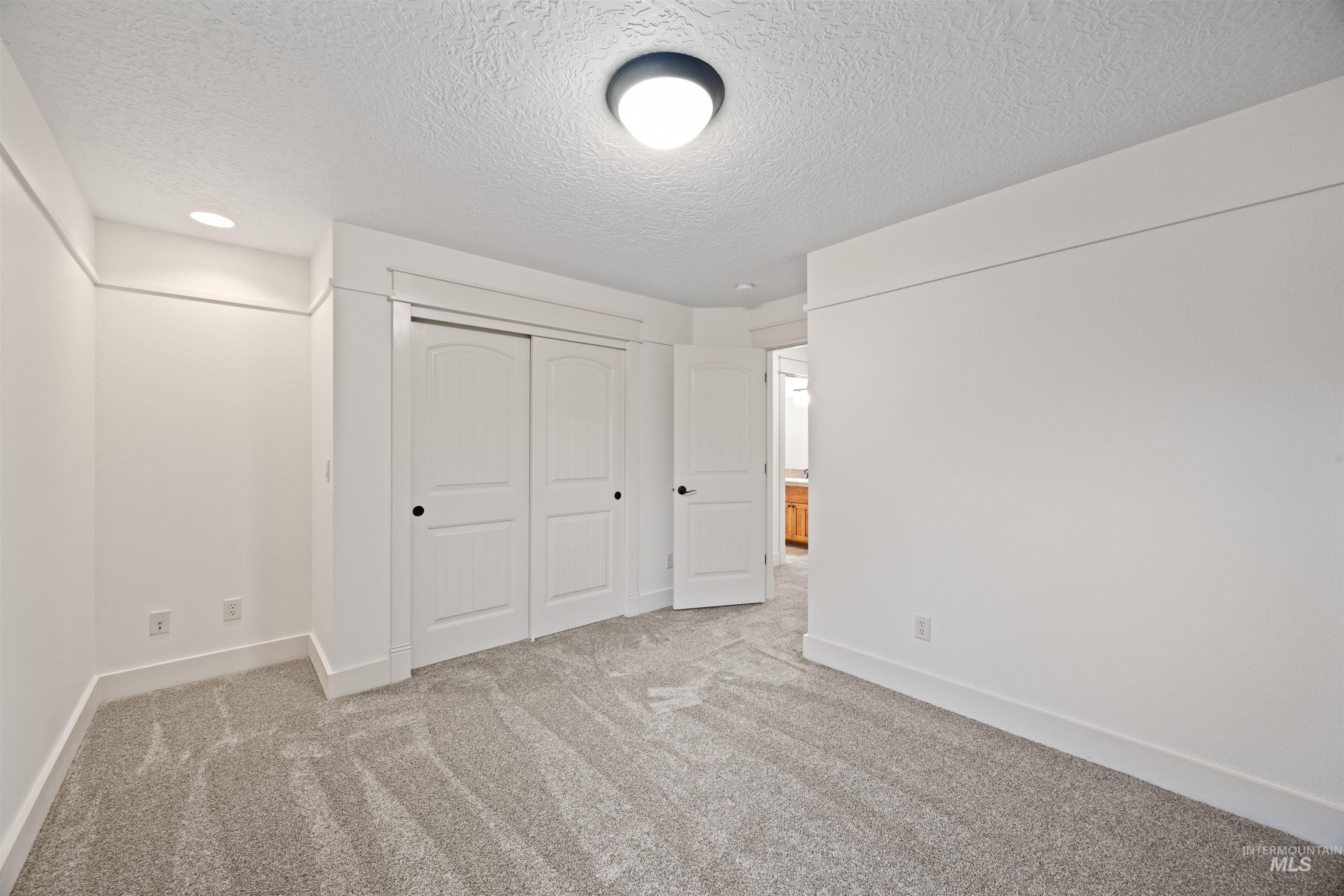 Unfurnished bedroom with a textured ceiling, a closet, and carpet floors