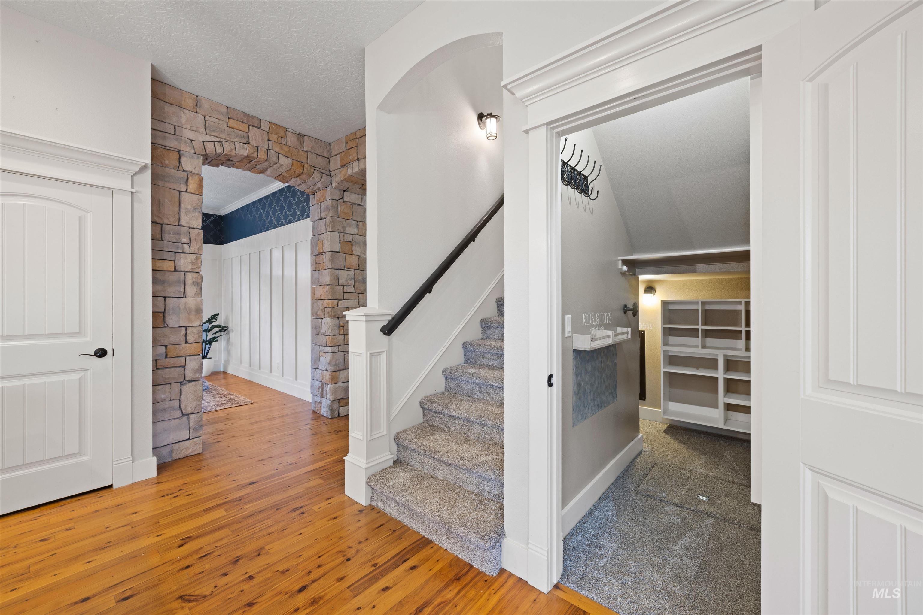 Staircase with arched walkways, a textured ceiling, and wood-type flooring