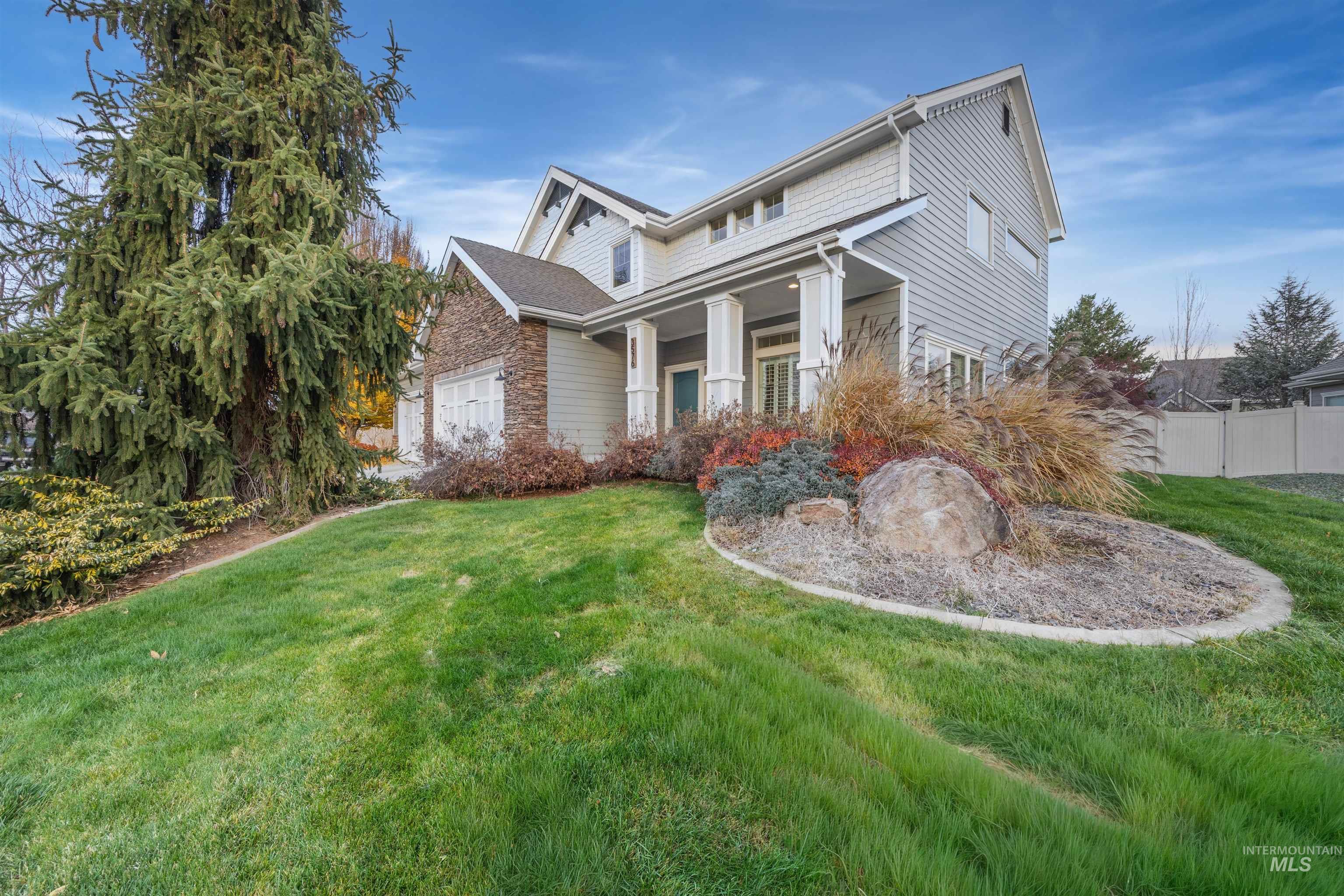 View of front facade featuring a porch, stone siding, and an attached garage