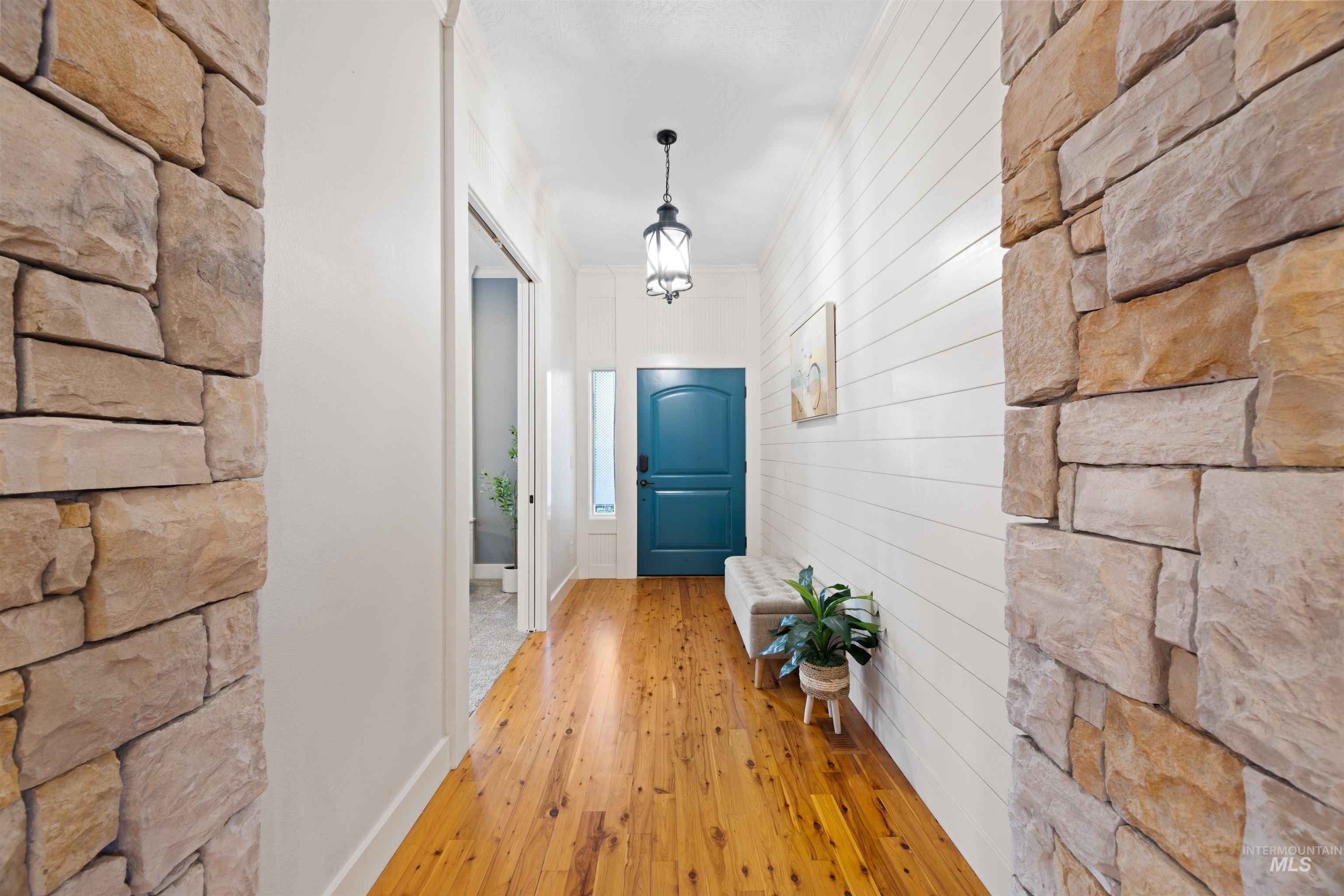 Hallway featuring wood-type flooring, a chandelier, and ornamental molding