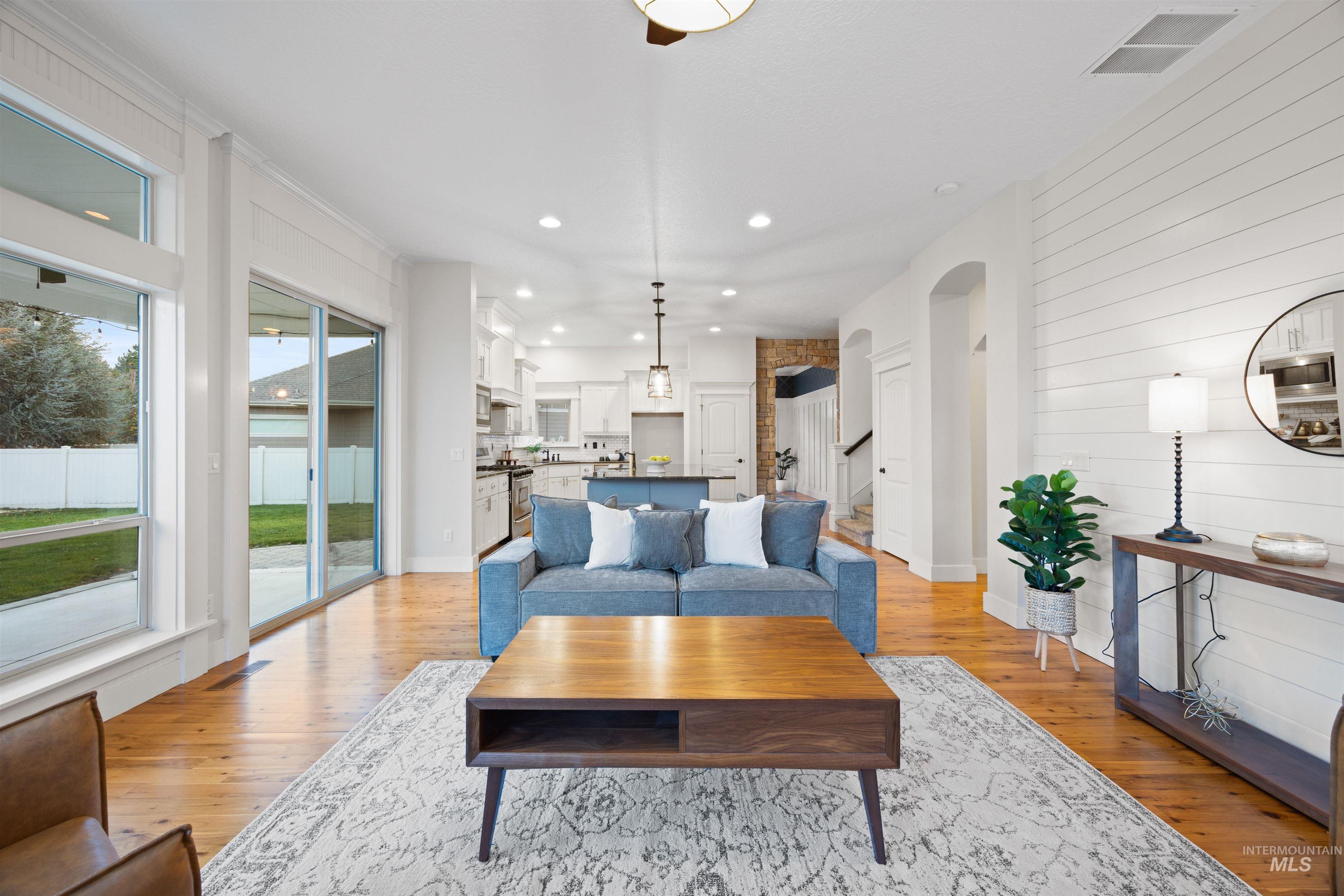 Living room featuring recessed lighting, light wood finished floors, wood walls, arched walkways, and stairway