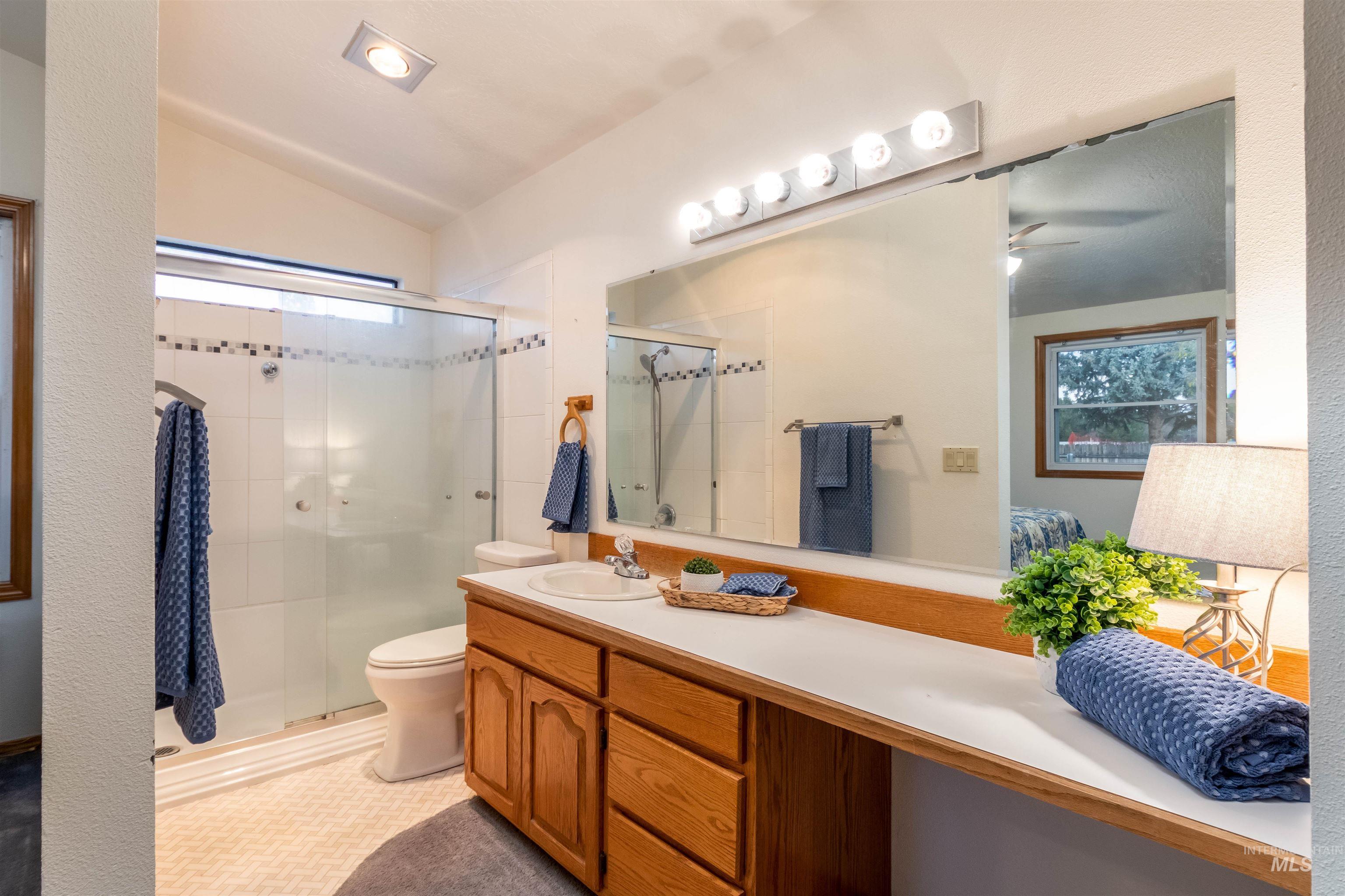 Bathroom featuring vanity, lofted ceiling, and a stall shower