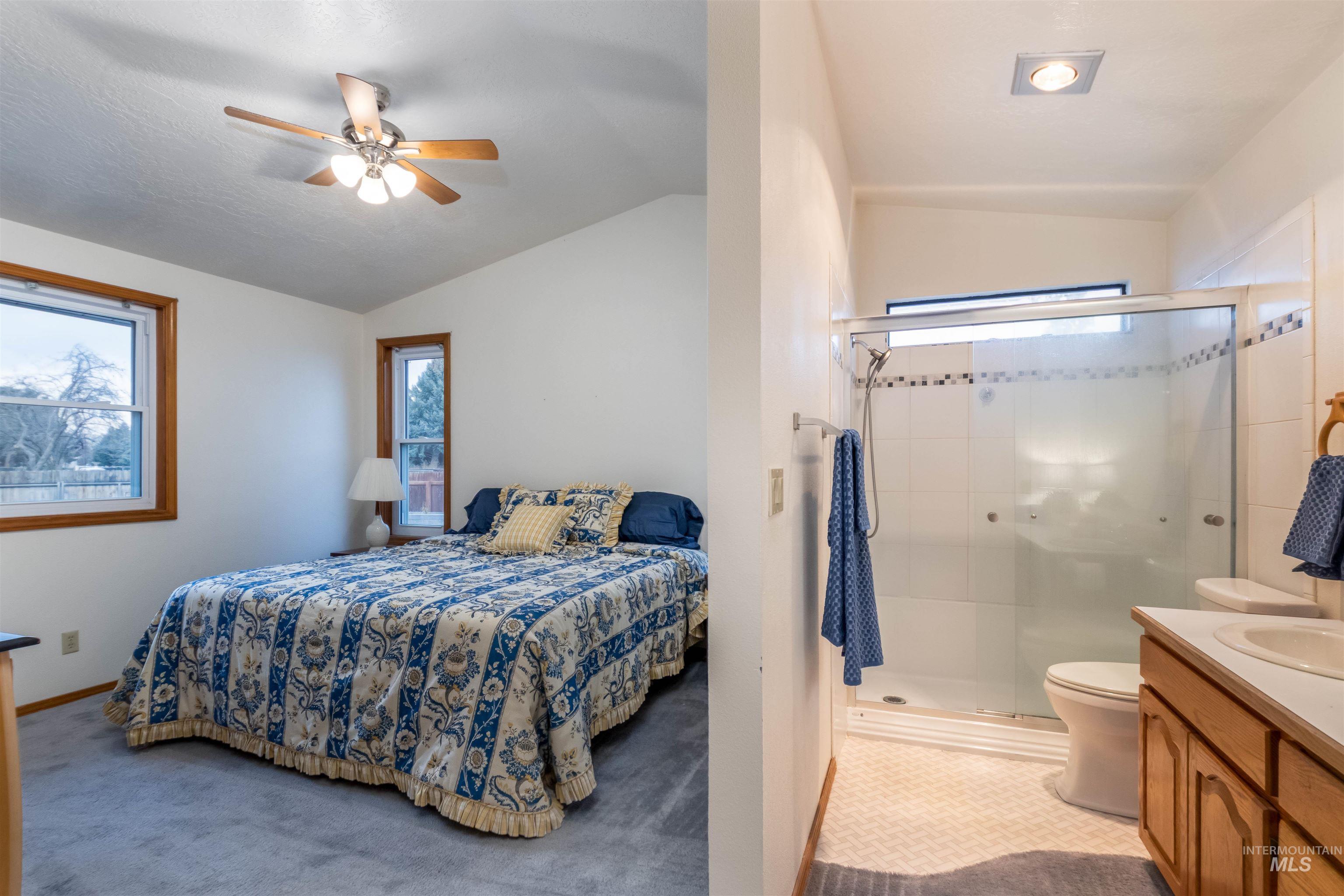 Bedroom featuring lofted ceiling, light colored carpet, and a ceiling fan