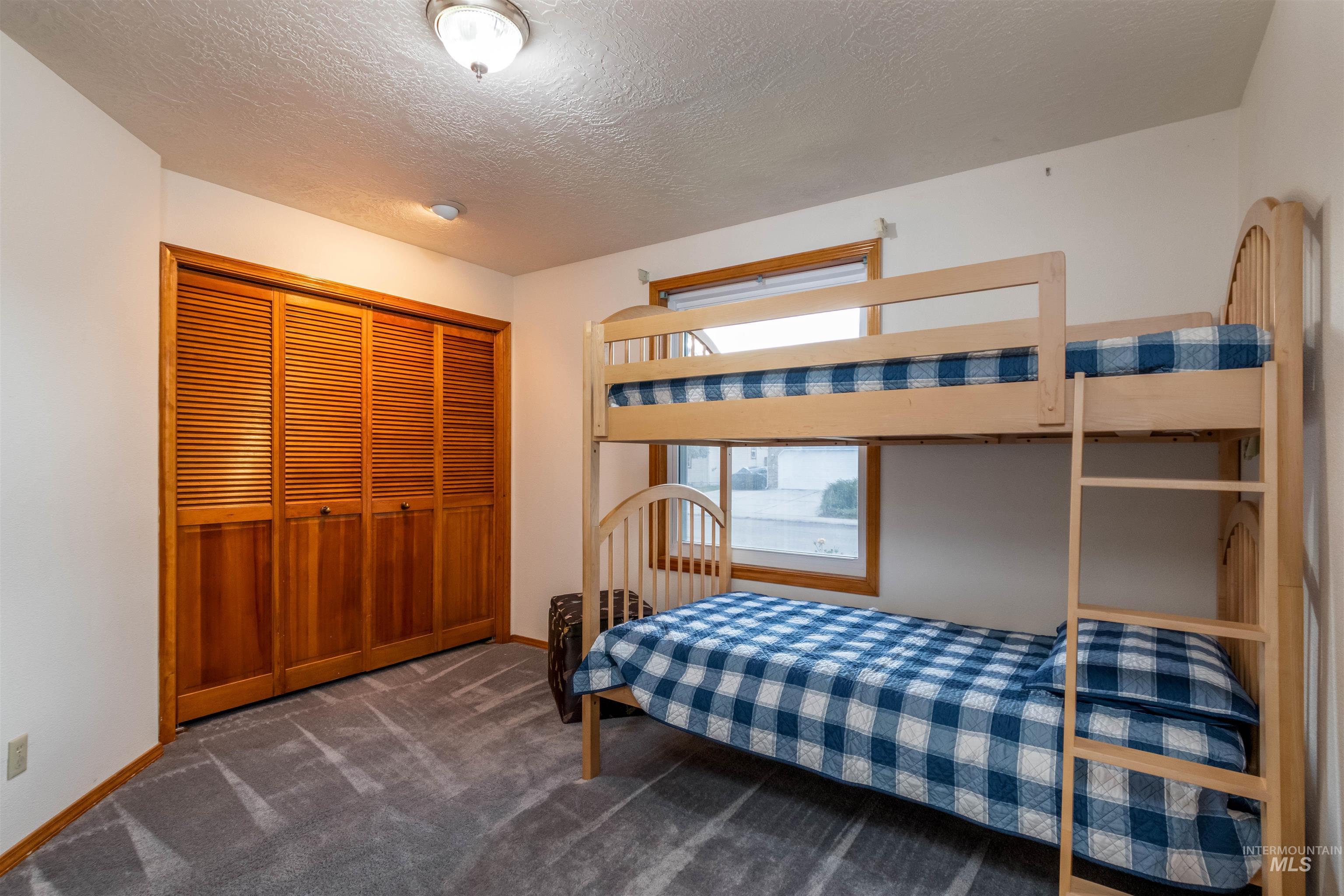 Bedroom featuring a textured ceiling, dark colored carpet, and a closet