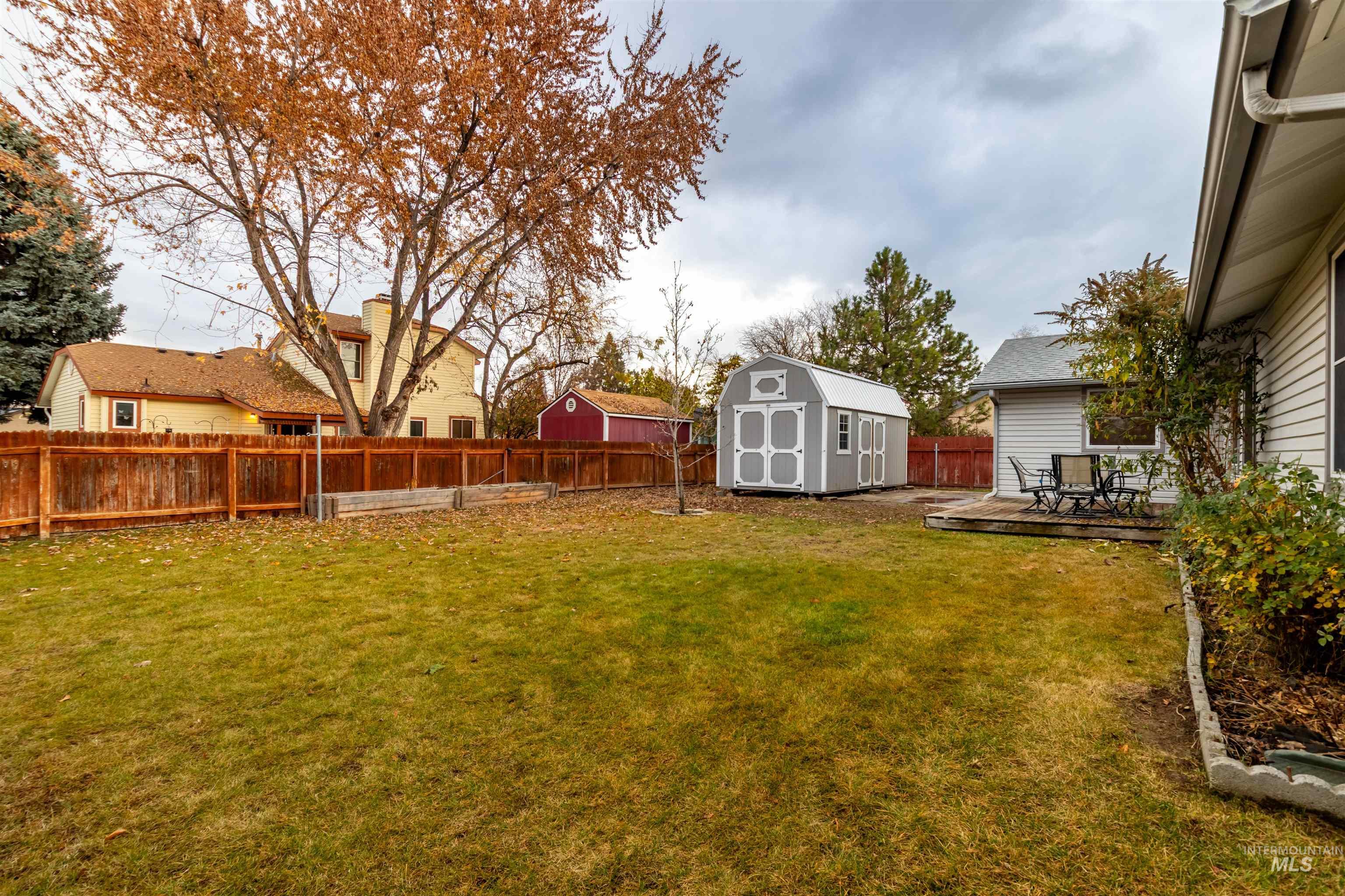 Fenced backyard featuring a storage unit and a deck