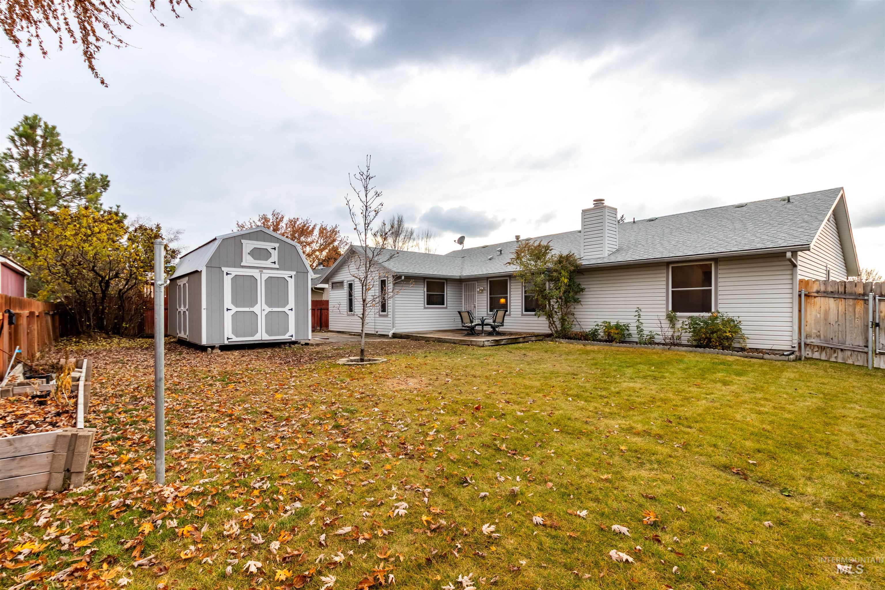 Rear view of house featuring a fenced backyard, a patio, a shed, and a chimney