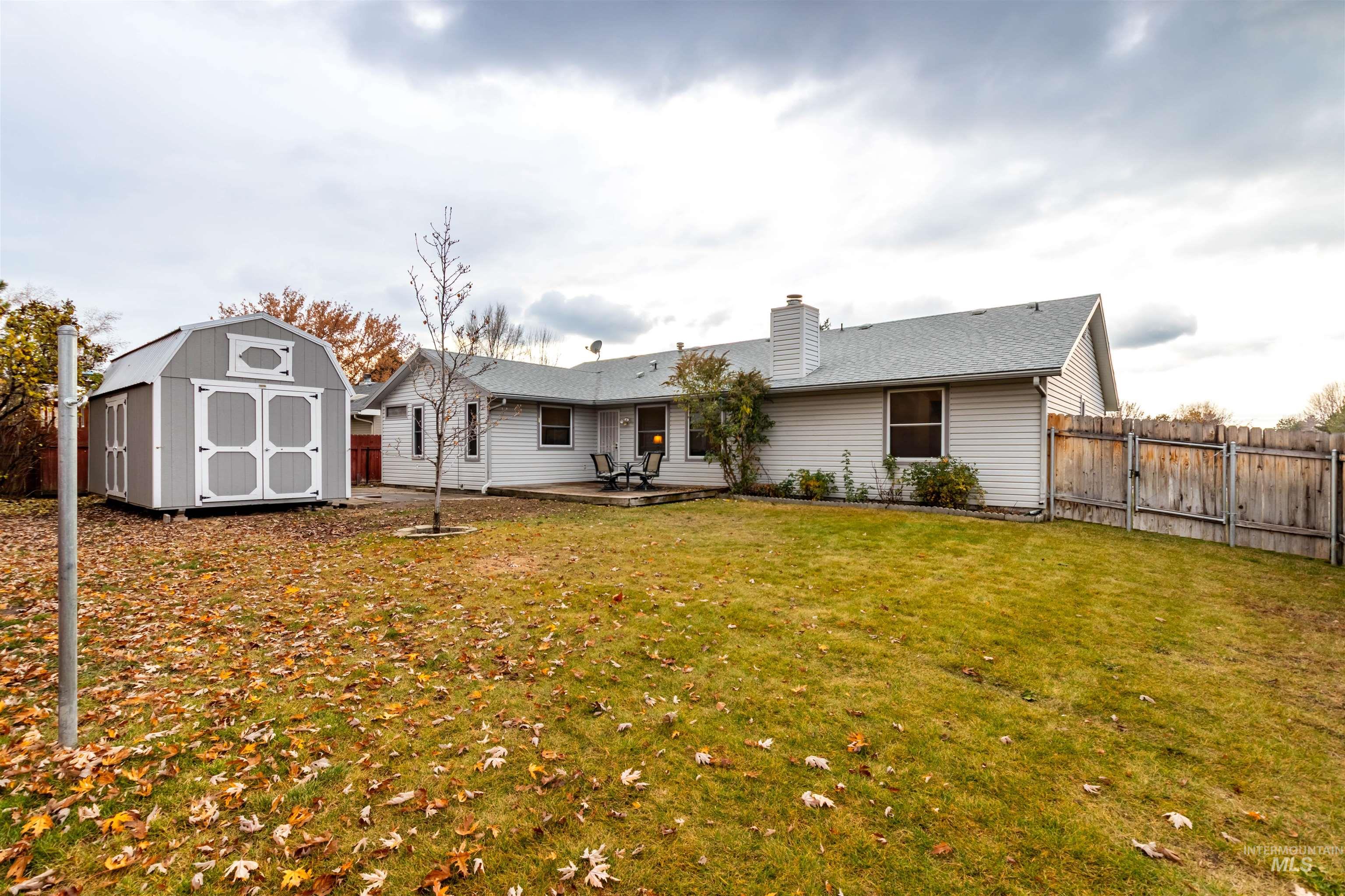 Rear view of property featuring a storage shed, a patio, a chimney, and a fenced backyard