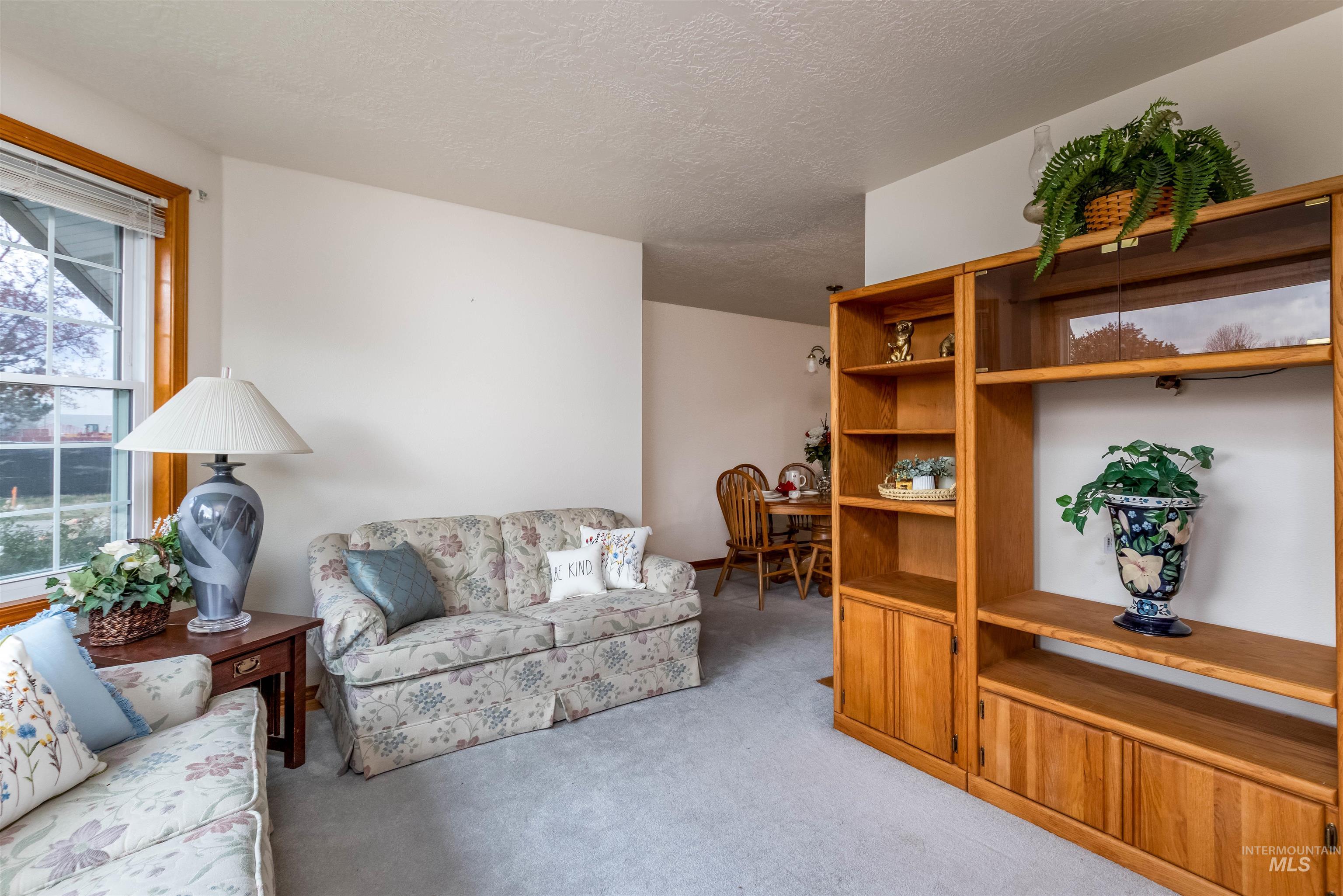 Living area featuring light colored carpet and a textured ceiling