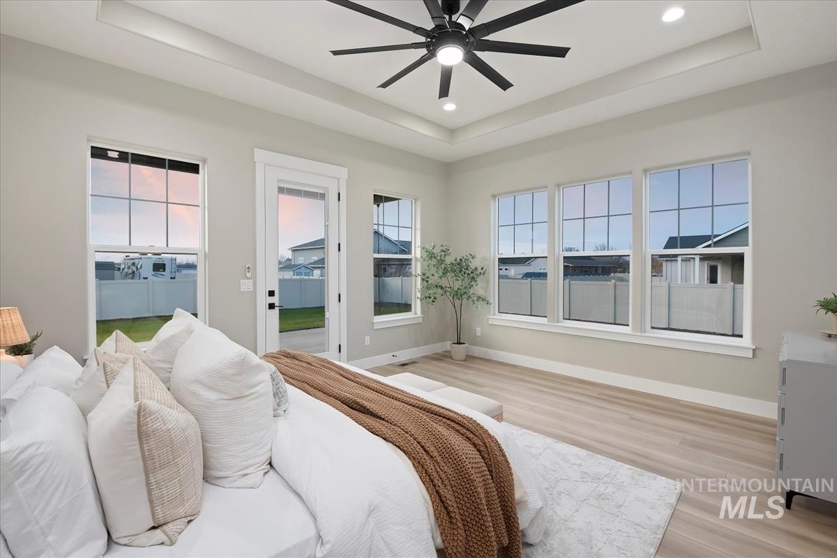 Bedroom featuring a tray ceiling, a ceiling fan, light wood-style flooring, access to exterior, and recessed lighting