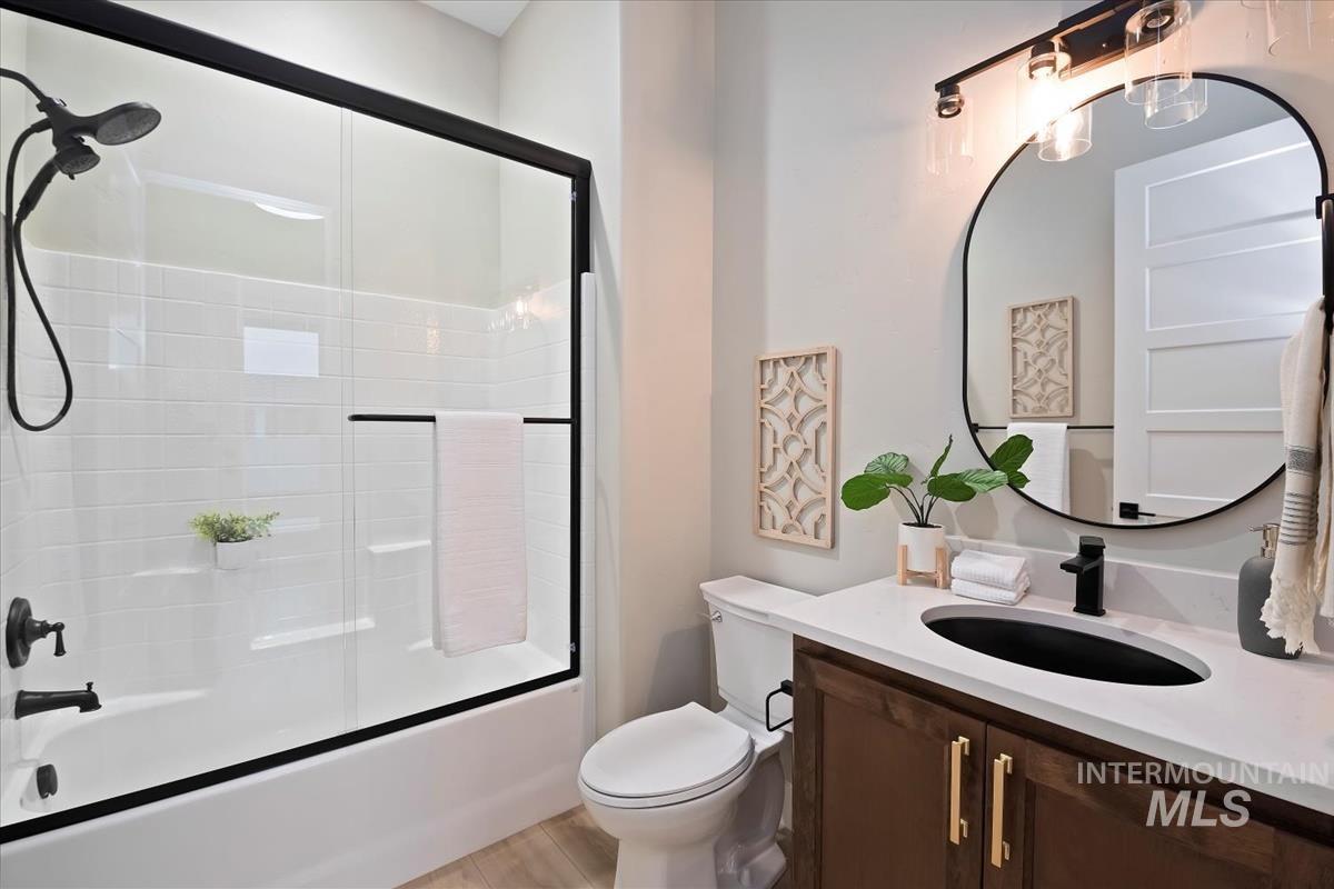 Full bathroom with enclosed tub / shower combo and vanity