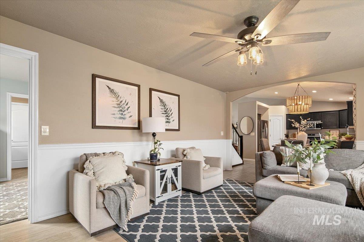 Living area featuring a chandelier, vaulted ceiling, wood finished floors, arched walkways, and stairs