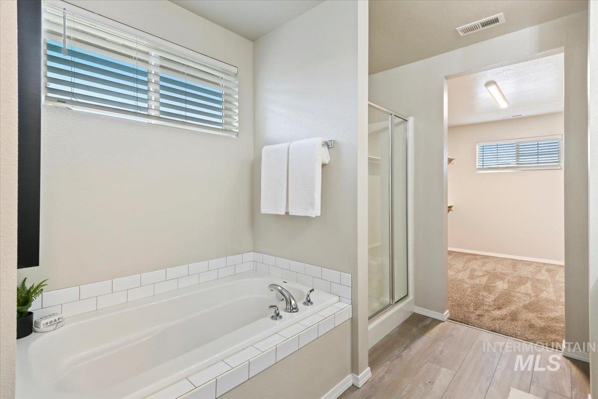 Full bath with light wood-style floors, a shower stall, a garden tub