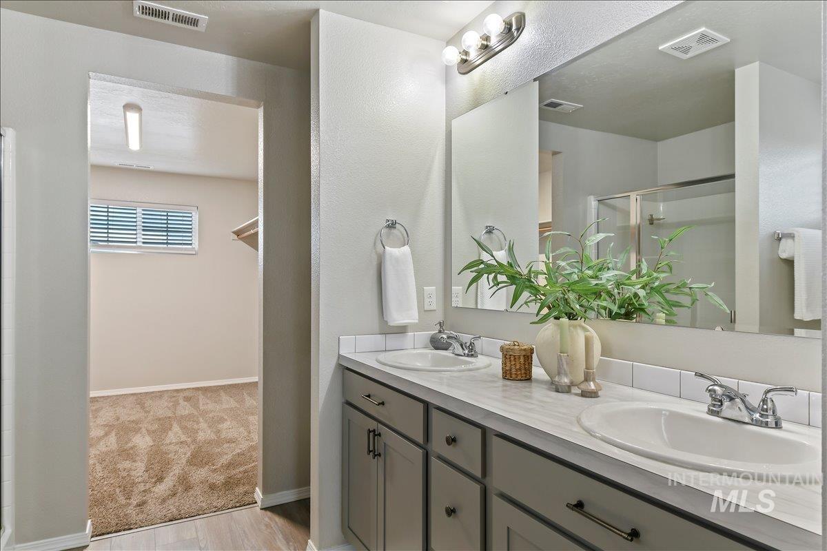 Bathroom featuring double vanity, a stall shower, and light colored carpet