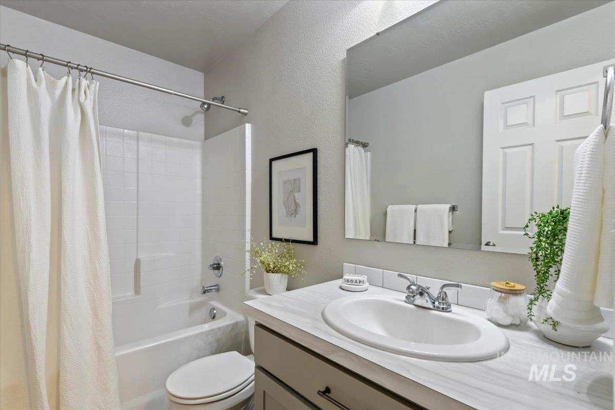 Bathroom with shower / tub combo with curtain, vanity, and a textured wall