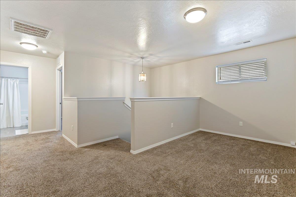 Unfurnished room with a textured ceiling and light colored carpet