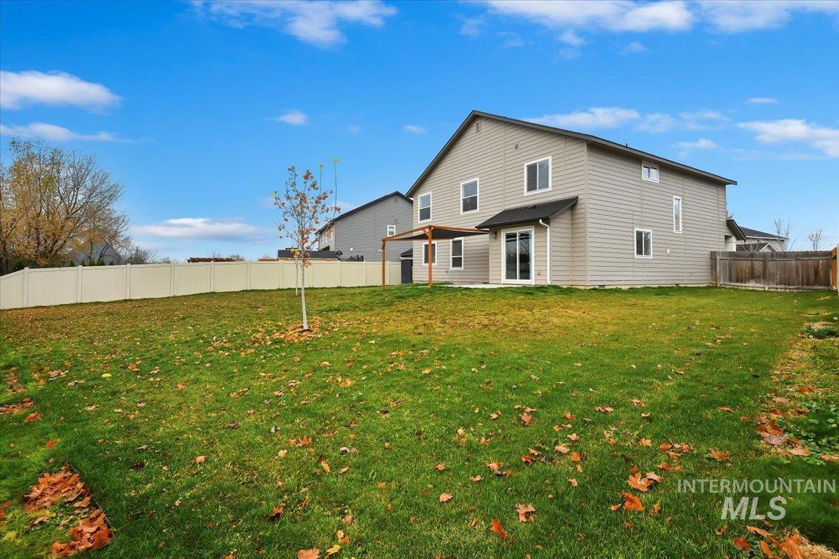 Rear view of house with a fenced backyard and a patio