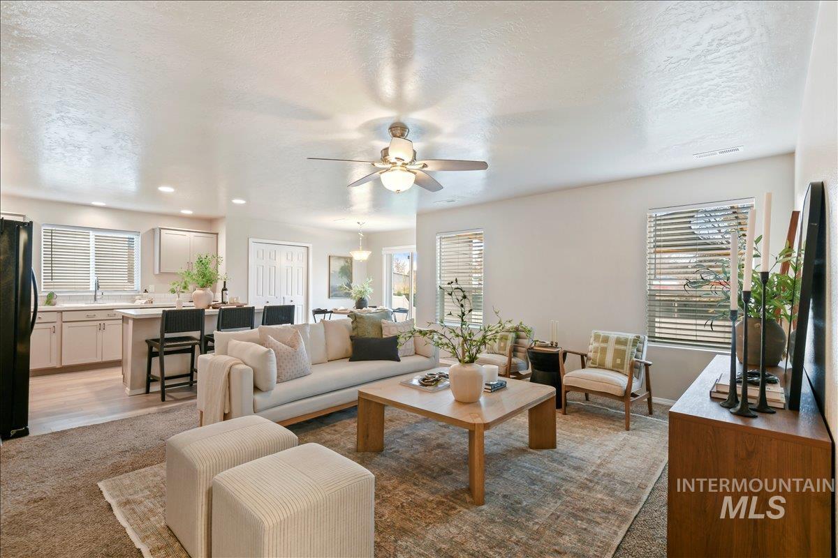 Living area featuring a textured ceiling, healthy amount of natural light, a ceiling fan, recessed lighting, and light carpet