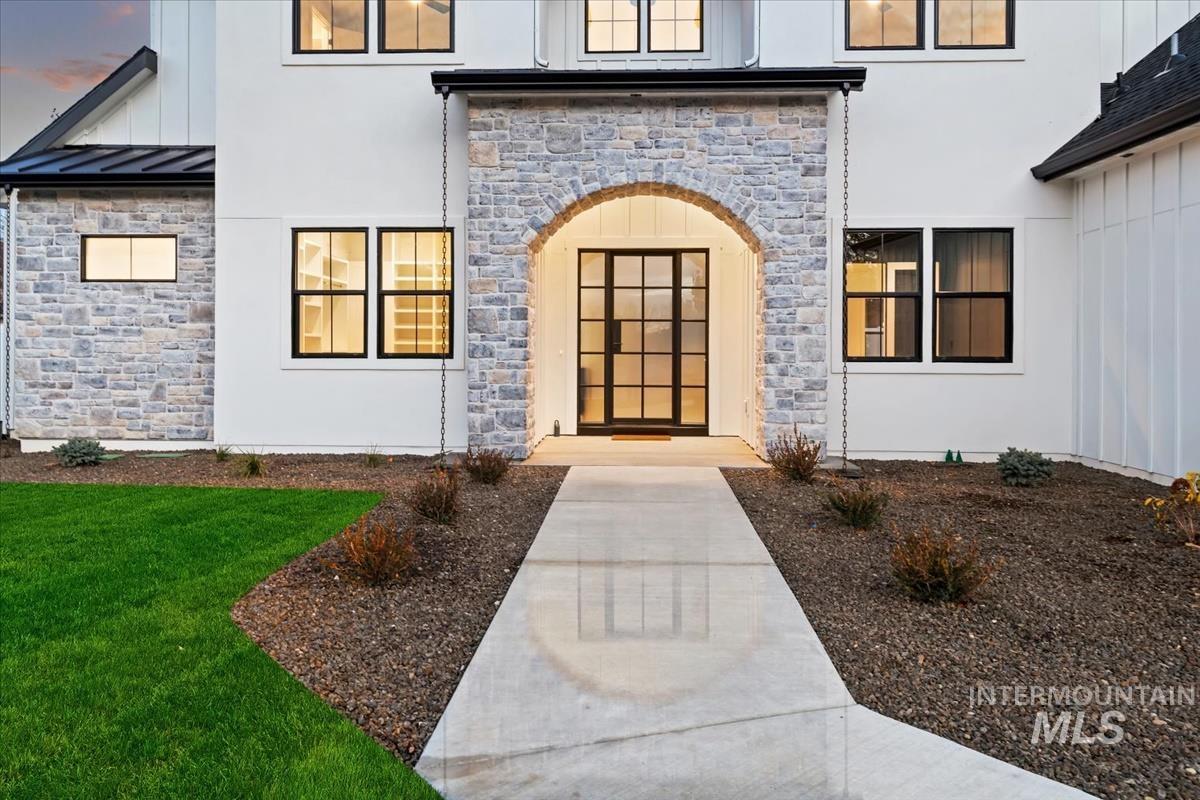 Doorway to property featuring stone siding, a standing seam roof, and stucco siding