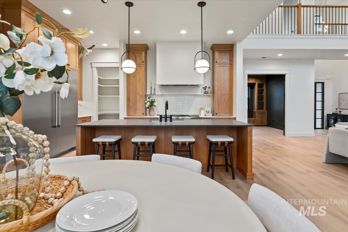 Kitchen featuring built in fridge, recessed lighting, decorative light fixtures, backsplash, and a kitchen bar