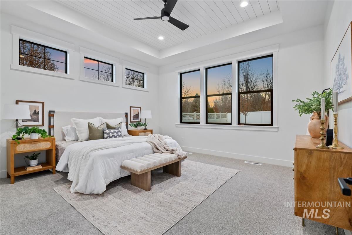 Bedroom with a raised ceiling, ceiling fan, light colored carpet, wooden ceiling, and recessed lighting