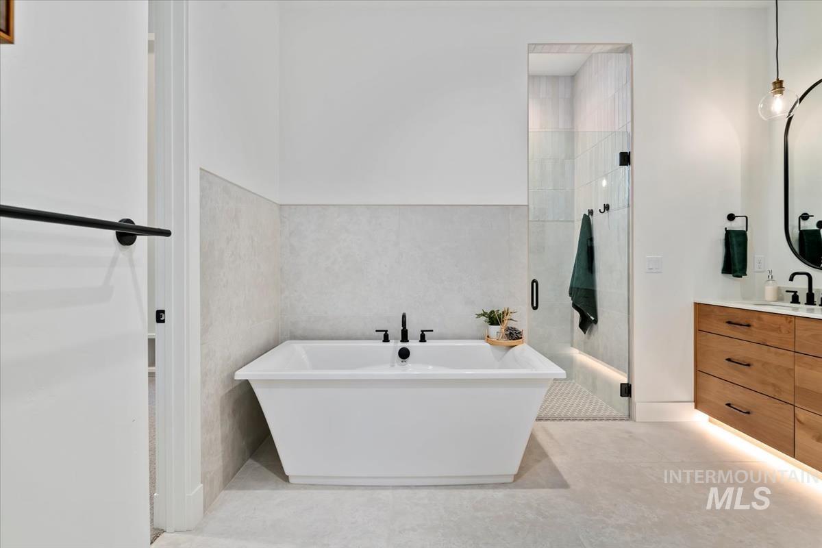 Bathroom with vanity, a soaking tub, a stall shower, tile walls, and light tile patterned floors