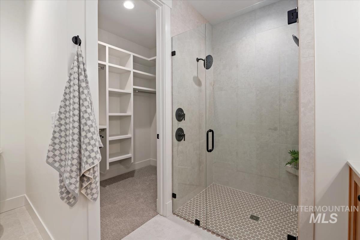 Full bathroom with a spacious closet, a shower stall, and recessed lighting