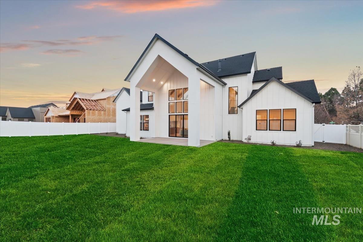 Back of property with board and batten siding, a fenced backyard, and a patio area