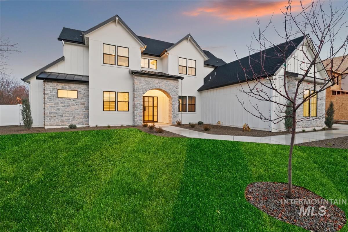 View of front of house featuring stone siding, a front yard, a standing seam roof, and a metal roof