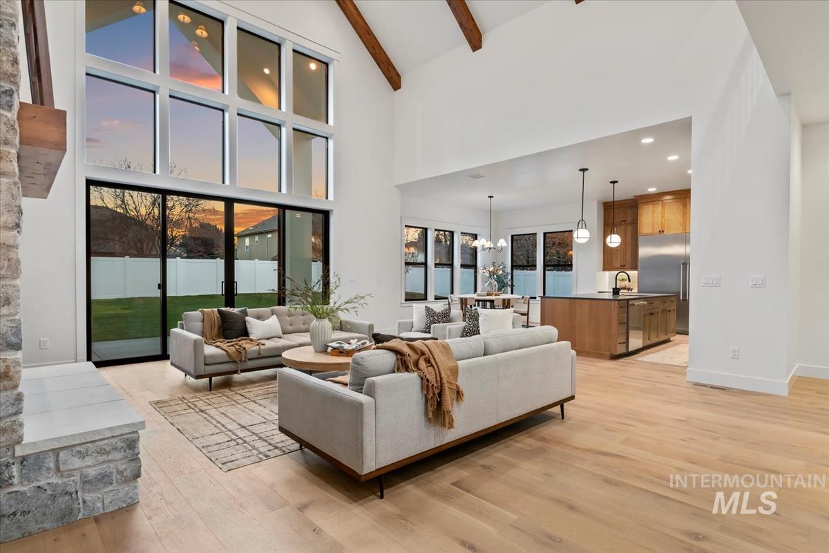 Living area with a chandelier, light wood-type flooring, beam ceiling, recessed lighting, and high vaulted ceiling