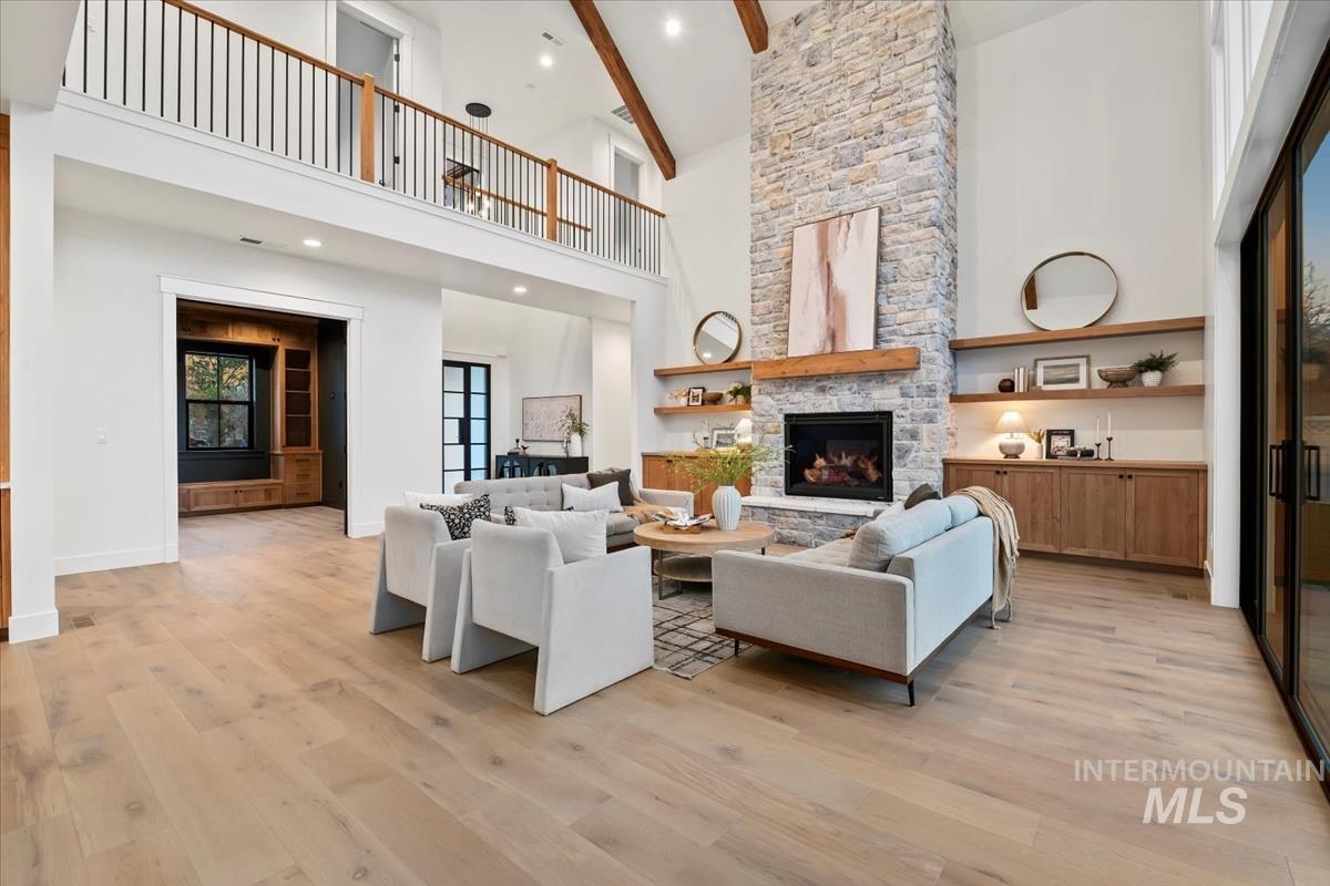 Living area featuring high vaulted ceiling, light wood-style flooring, a fireplace, beamed ceiling, and recessed lighting