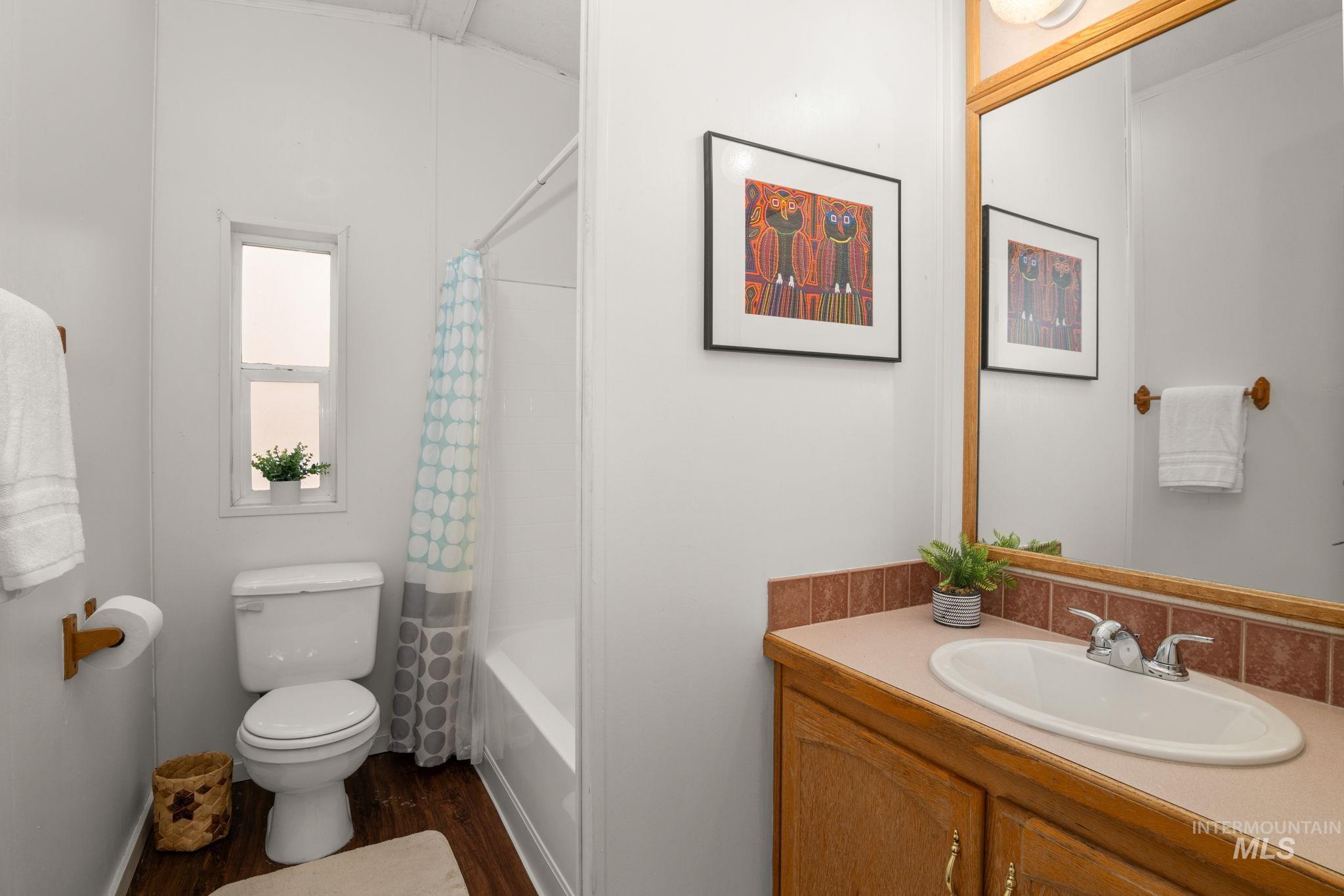 Bathroom with vanity, shower / bathtub combination with curtain, and dark wood-style floors