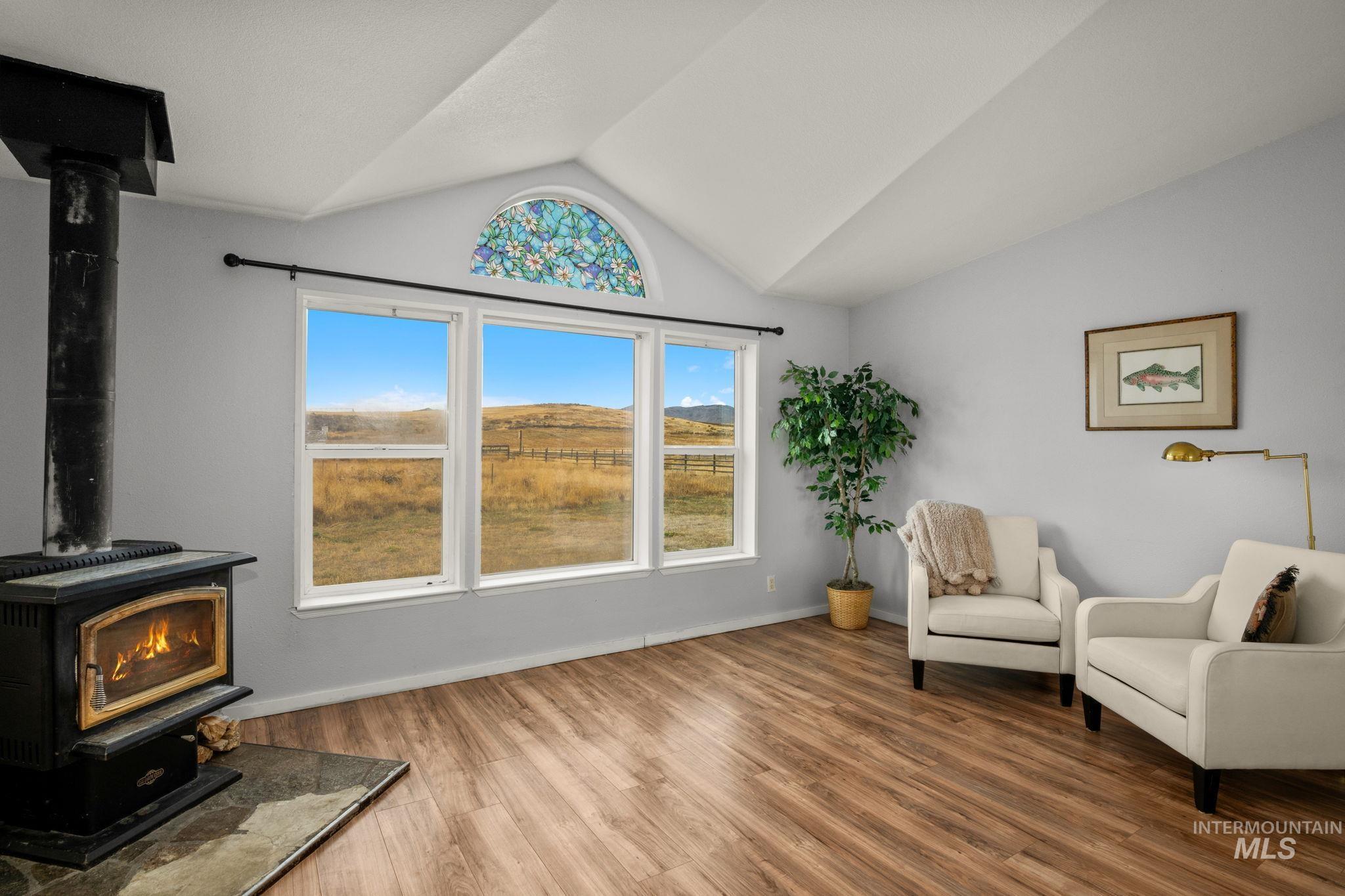 Sitting room featuring a wood stove, lofted ceiling, and wood finished floors