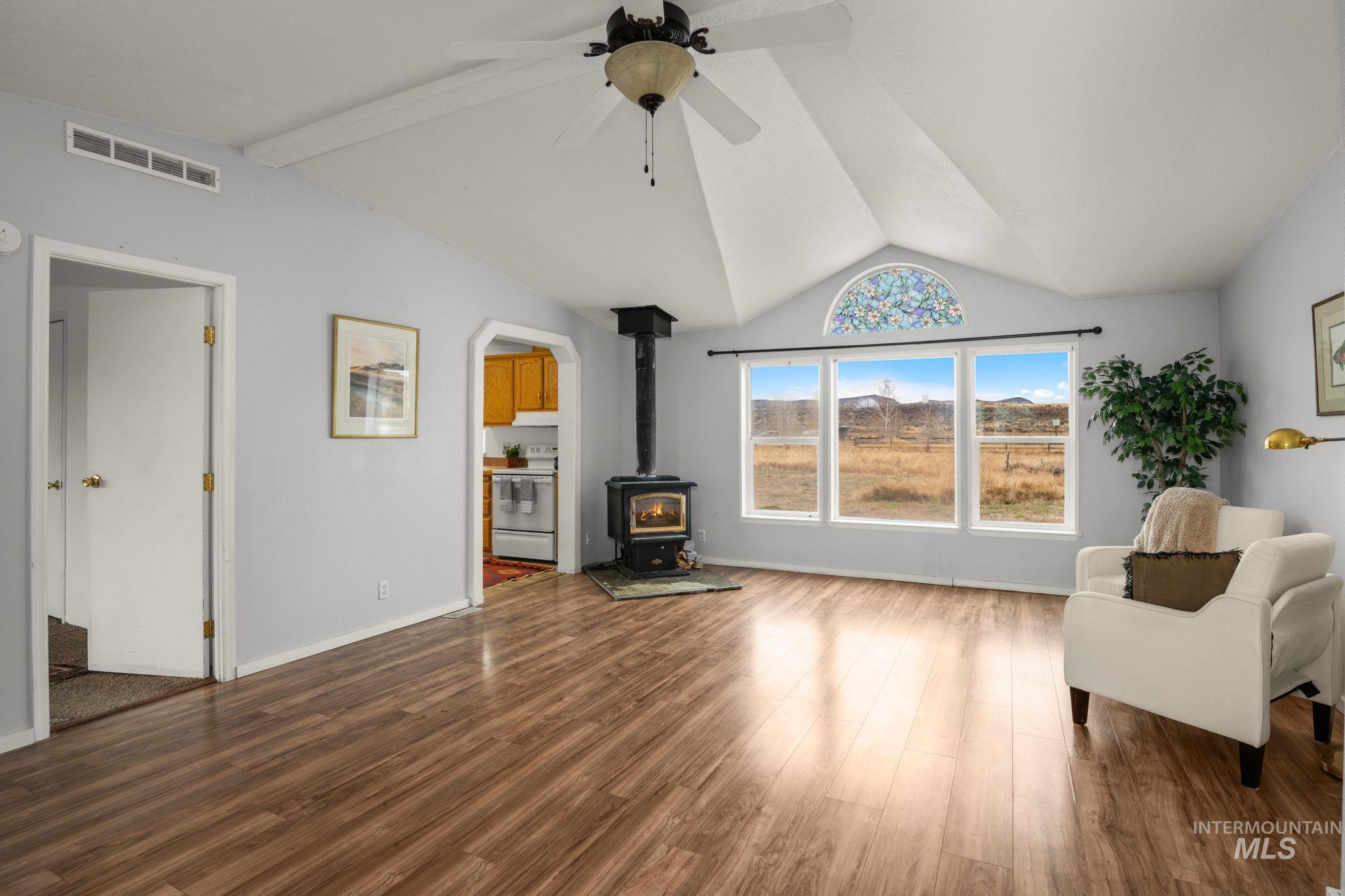 Living area featuring a wood stove, dark wood-type flooring, and ceiling fan