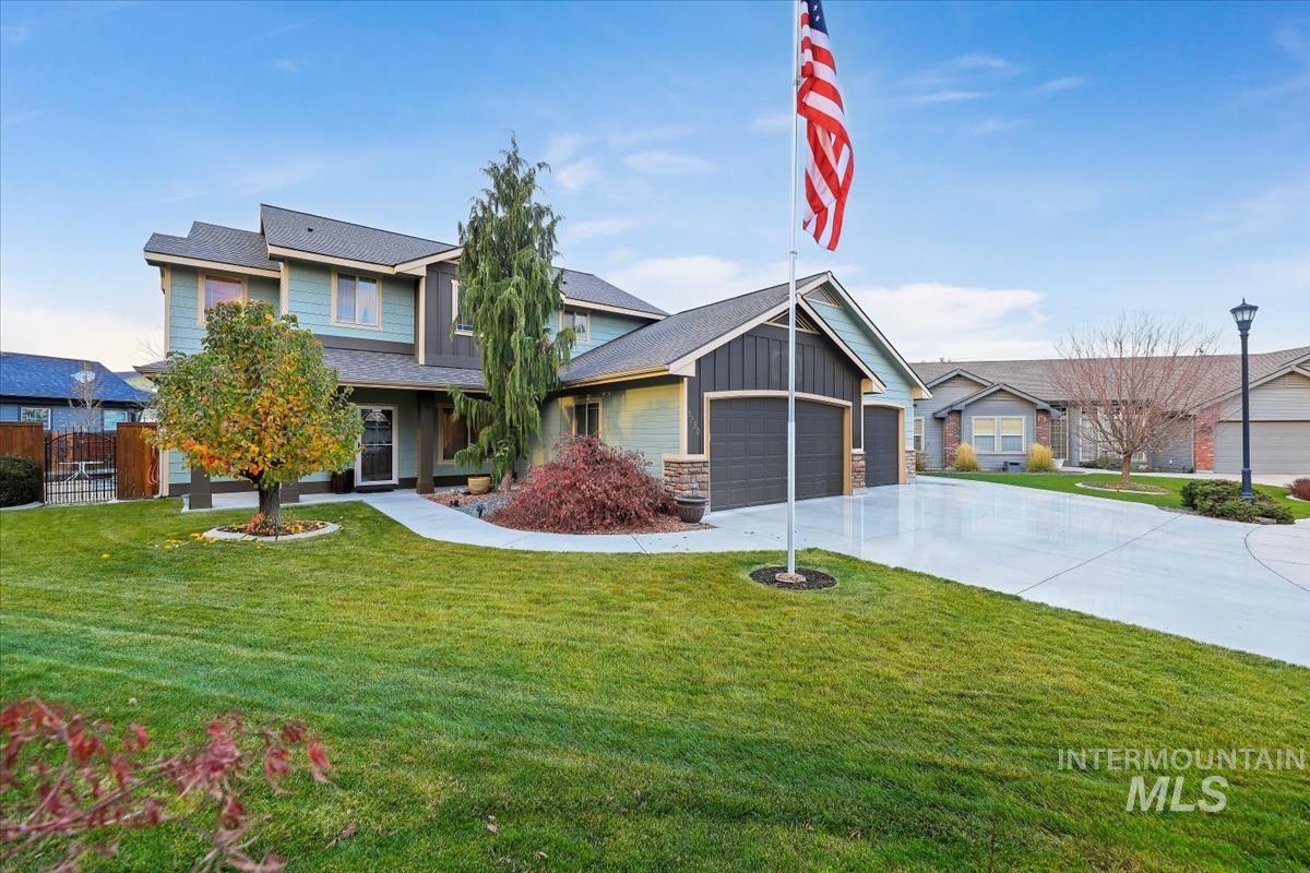 View of front of home featuring board and batten siding, driveway, a front yard, a garage, and stone siding