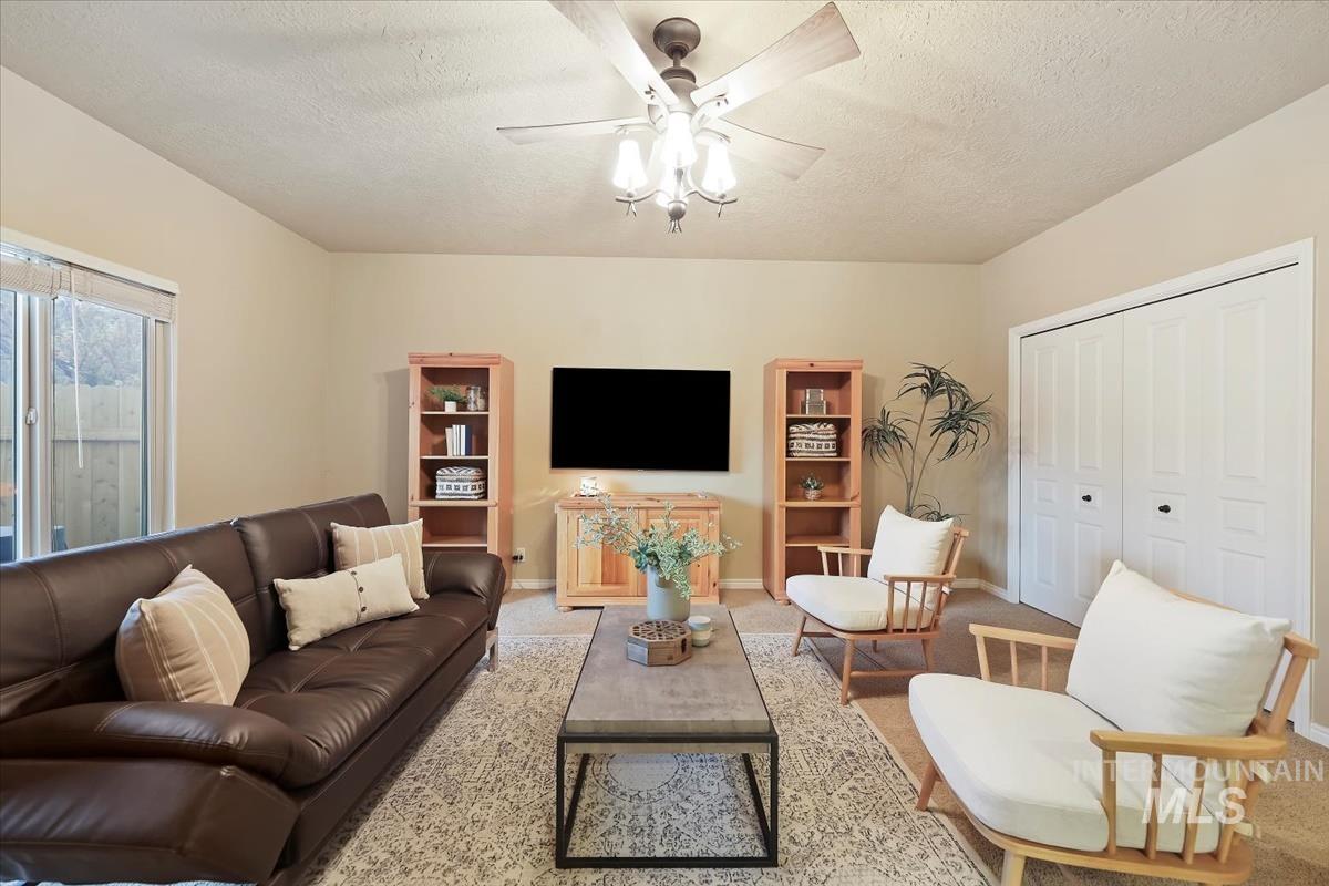 Living area with a textured ceiling, ceiling fan, and carpet floors