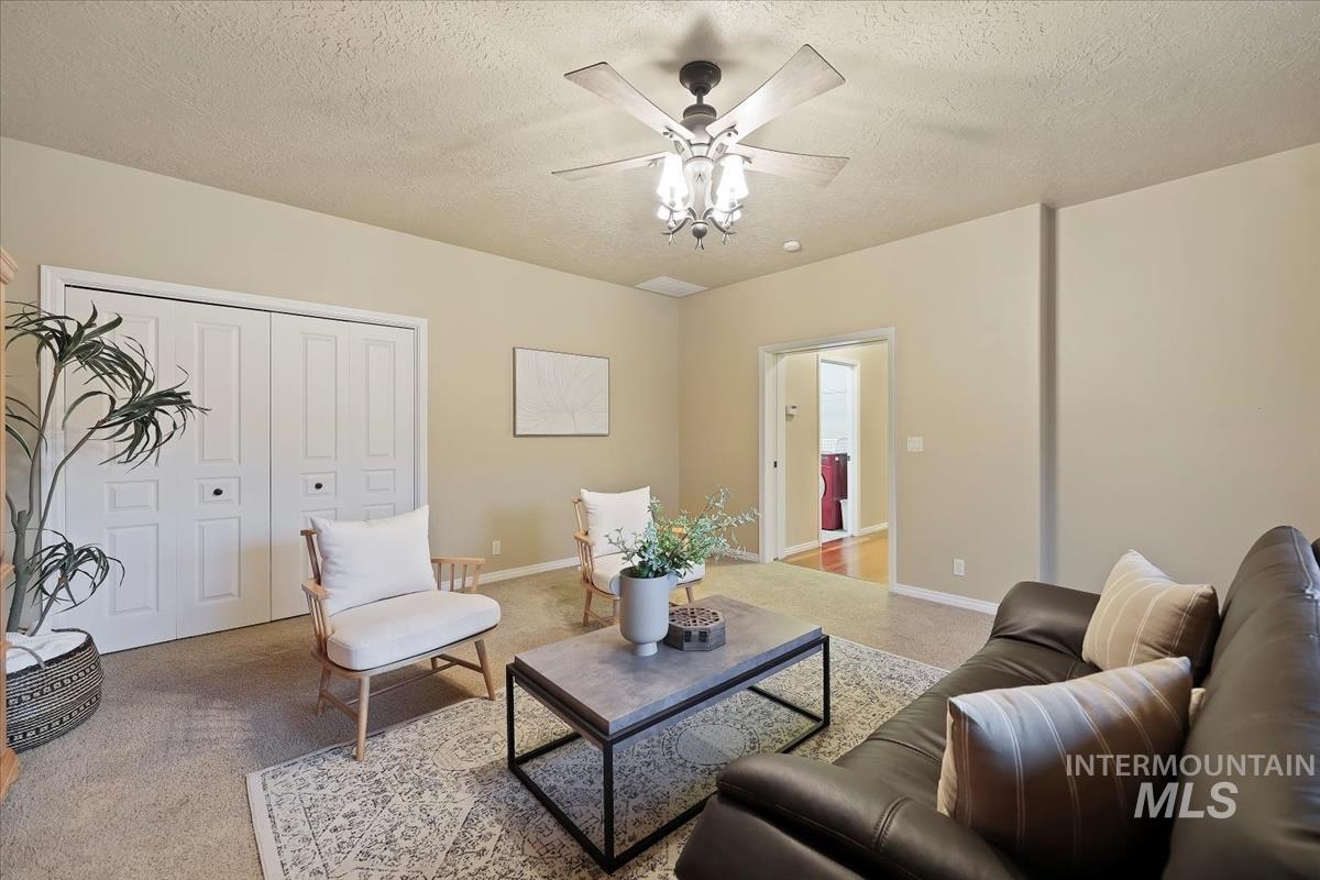 Living area with a textured ceiling, a ceiling fan, and carpet