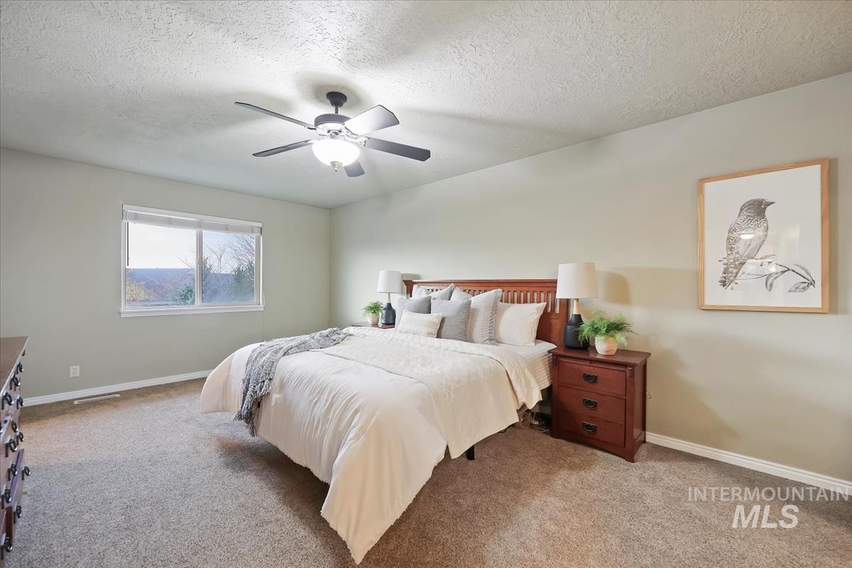 Bedroom featuring a textured ceiling, carpet flooring, and a ceiling fan
