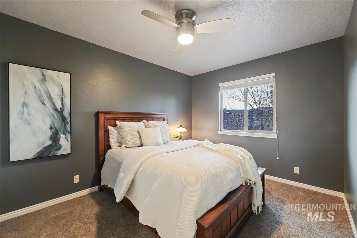 Carpeted bedroom with a textured ceiling and a ceiling fan