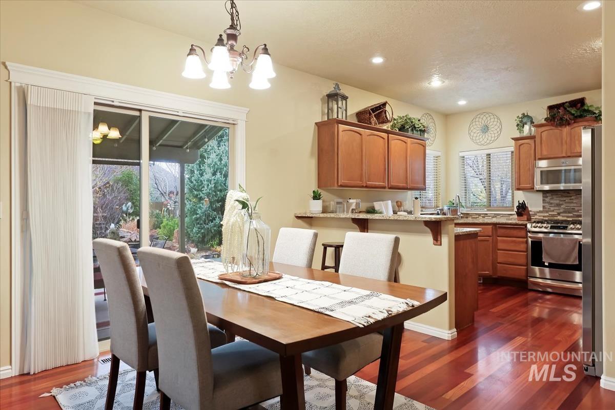 Dining space with dark wood-type flooring, a chandelier, and recessed lighting