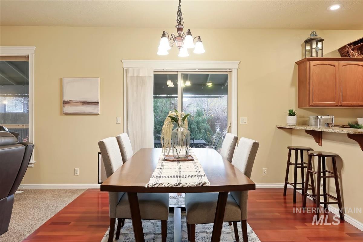 Dining space with a chandelier and dark wood-style flooring