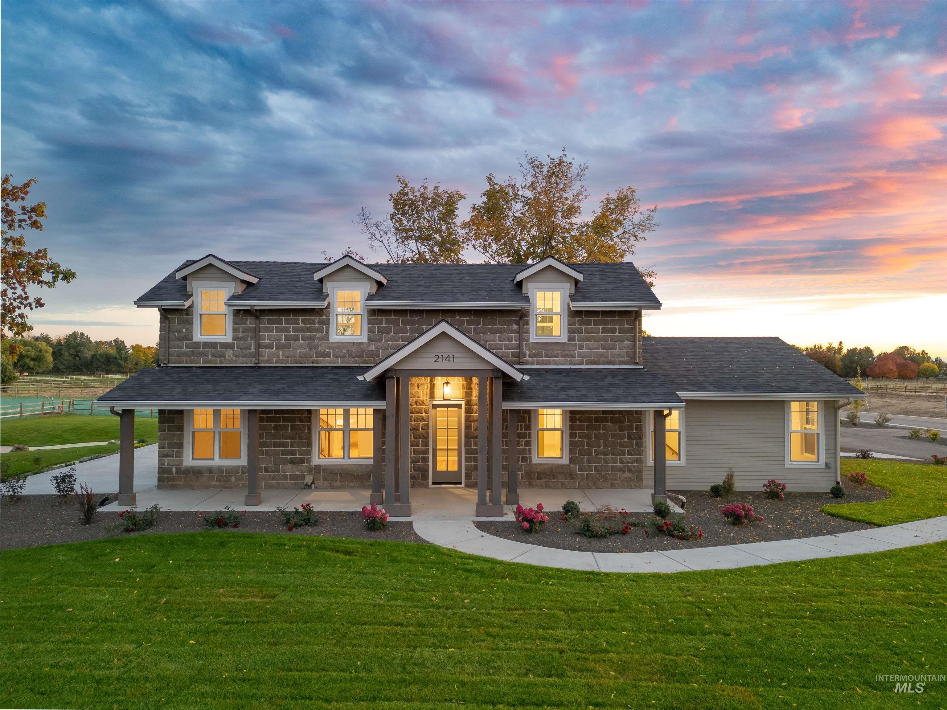 Shingle-style home featuring roof with shingles, a front lawn, covered porch, and stone siding