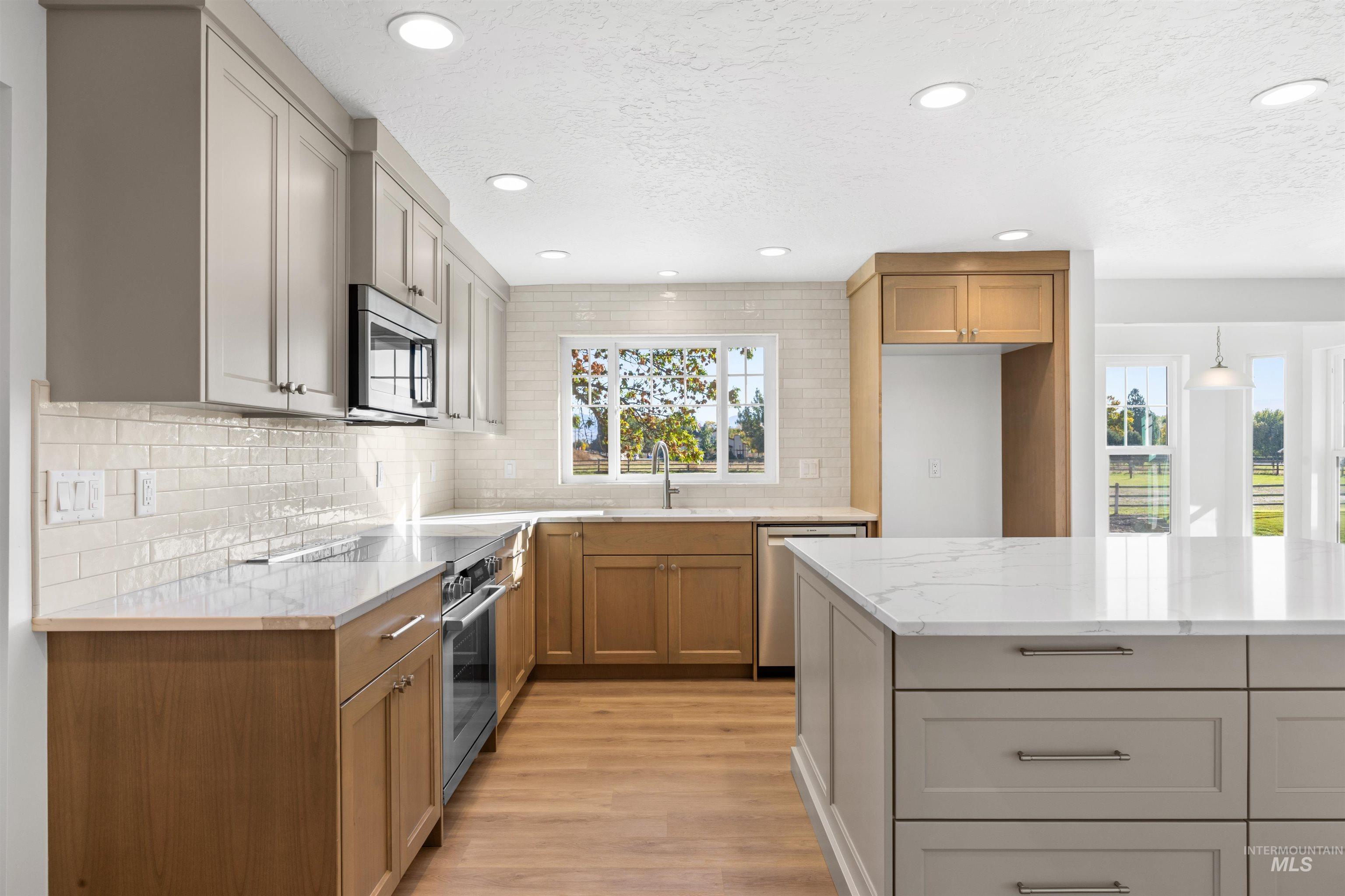 Kitchen featuring recessed lighting, light stone countertops, light wood finished floors, stainless steel appliances, and backsplash