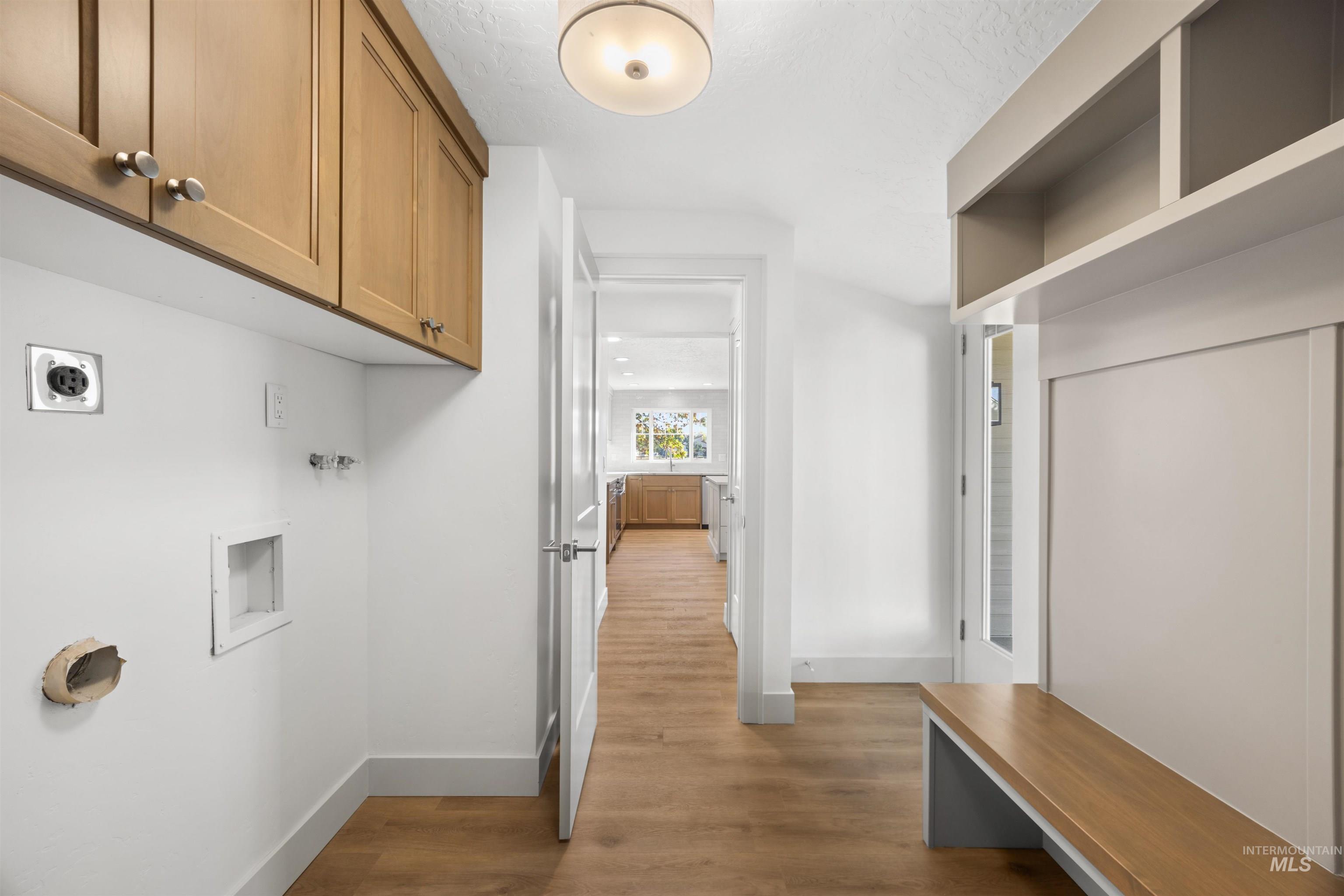 Washroom with washer hookup, light wood-type flooring, electric dryer hookup, and cabinet space