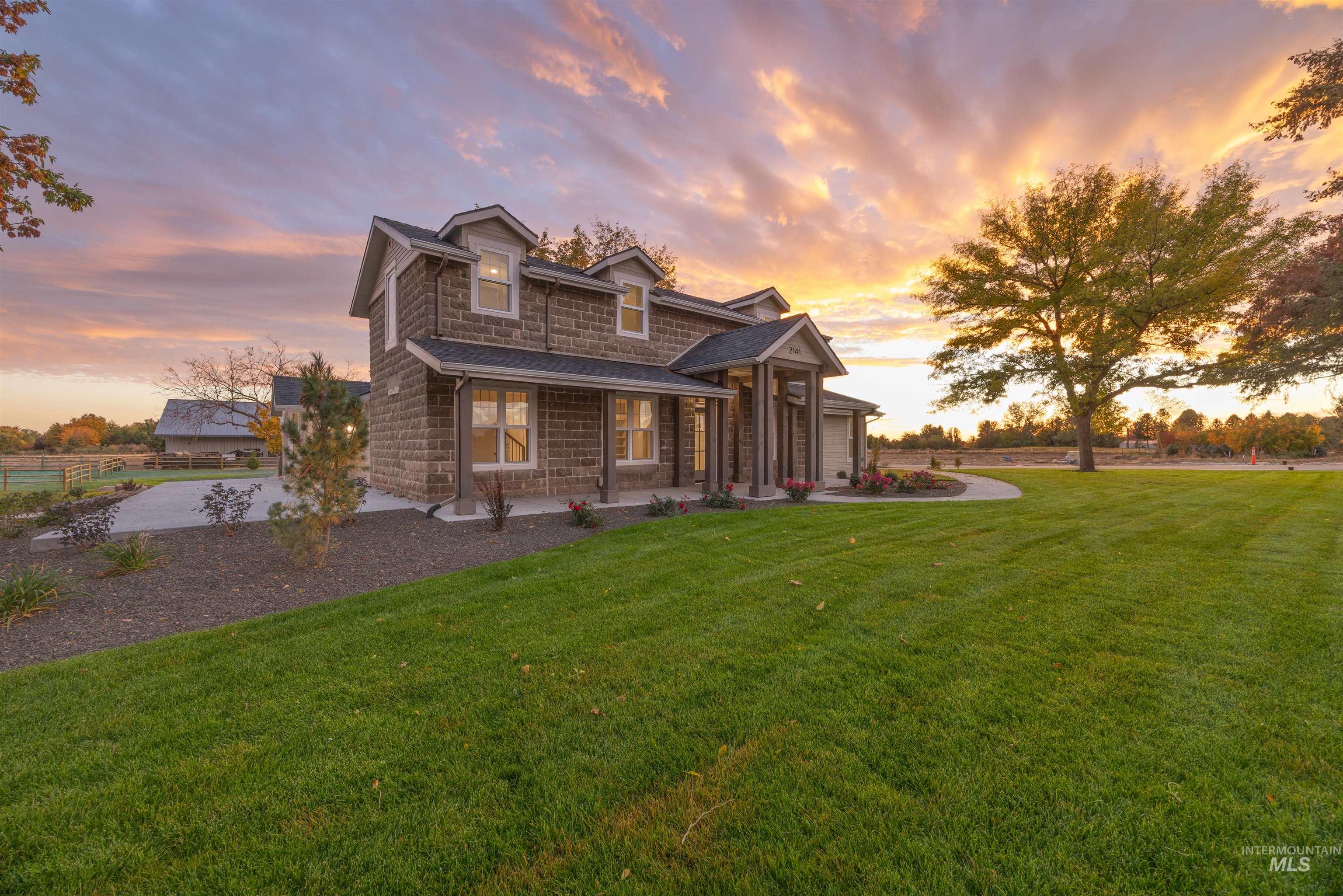 View of front facade featuring a front lawn, stone siding, and a porch