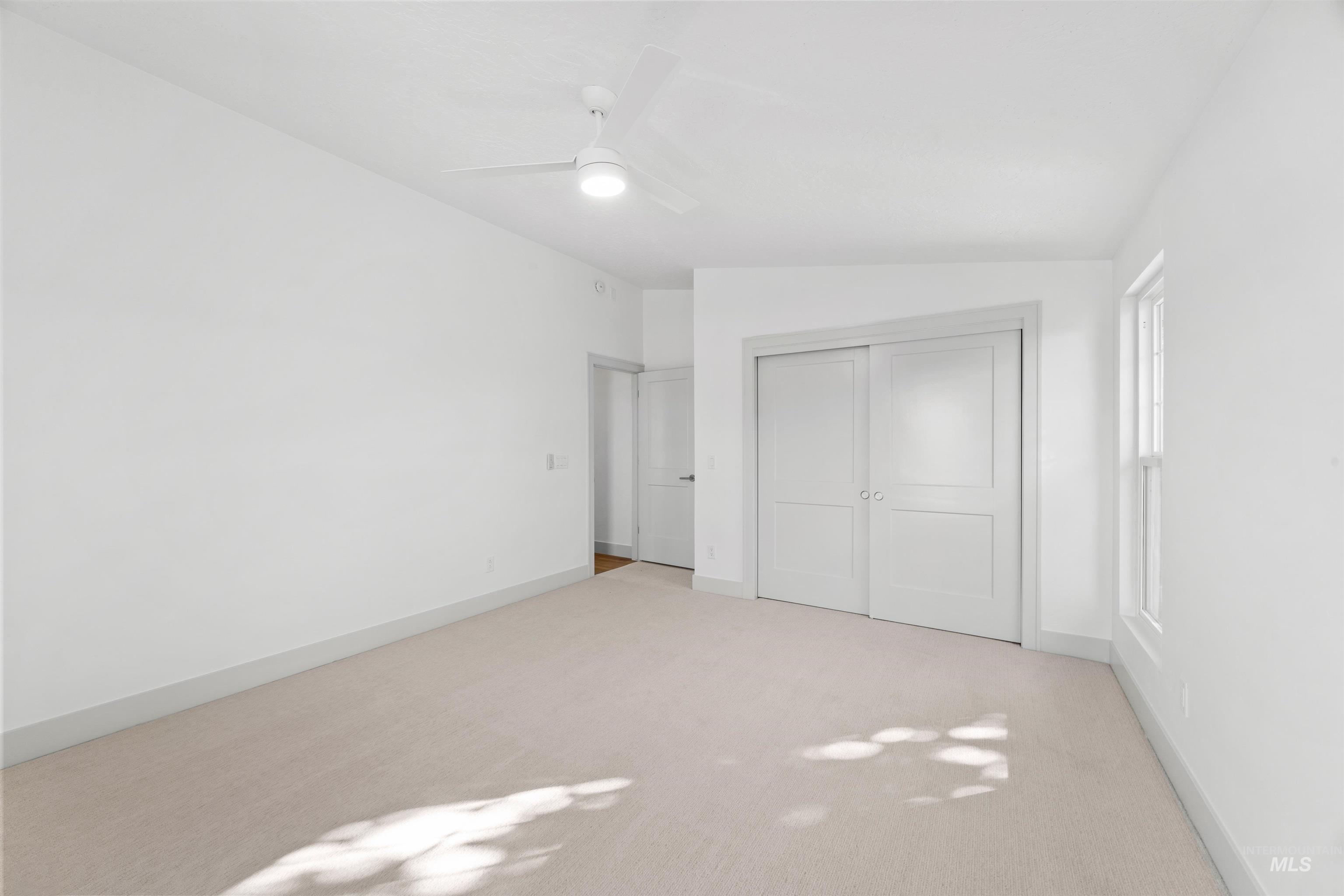 Unfurnished bedroom with carpet floors, a closet, a ceiling fan, and lofted ceiling