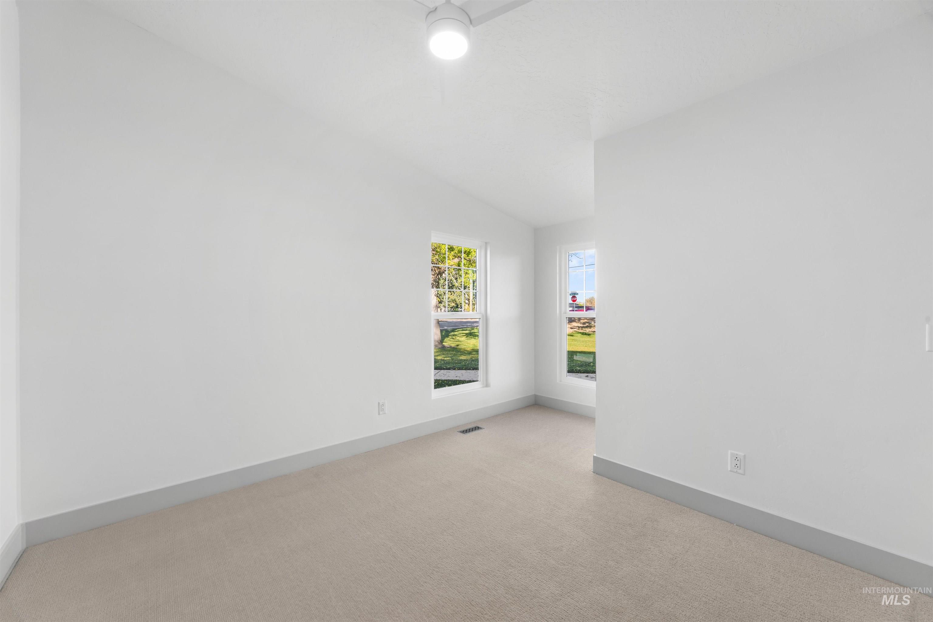Unfurnished room featuring lofted ceiling and light carpet