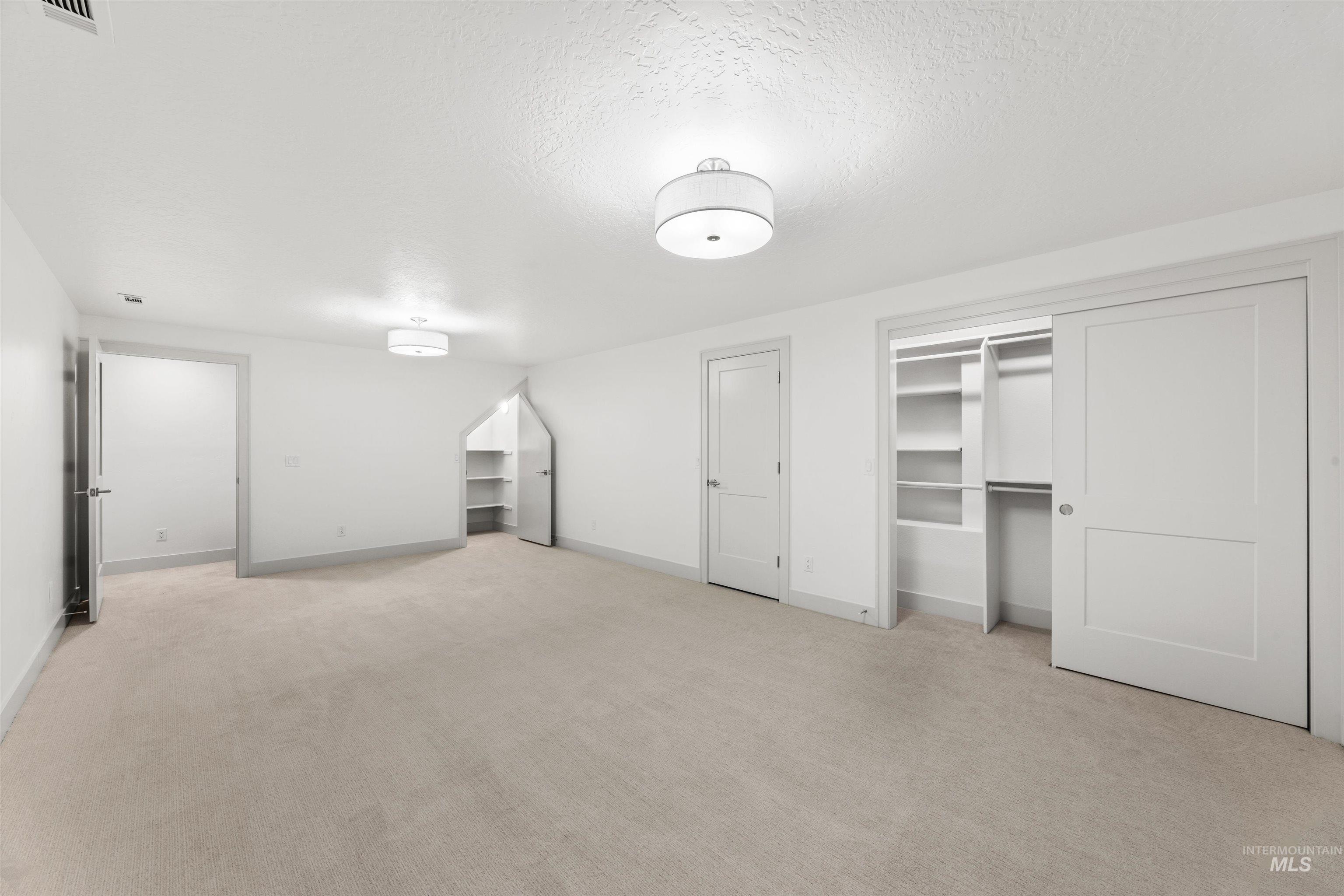 Unfurnished bedroom with a textured ceiling and light carpet