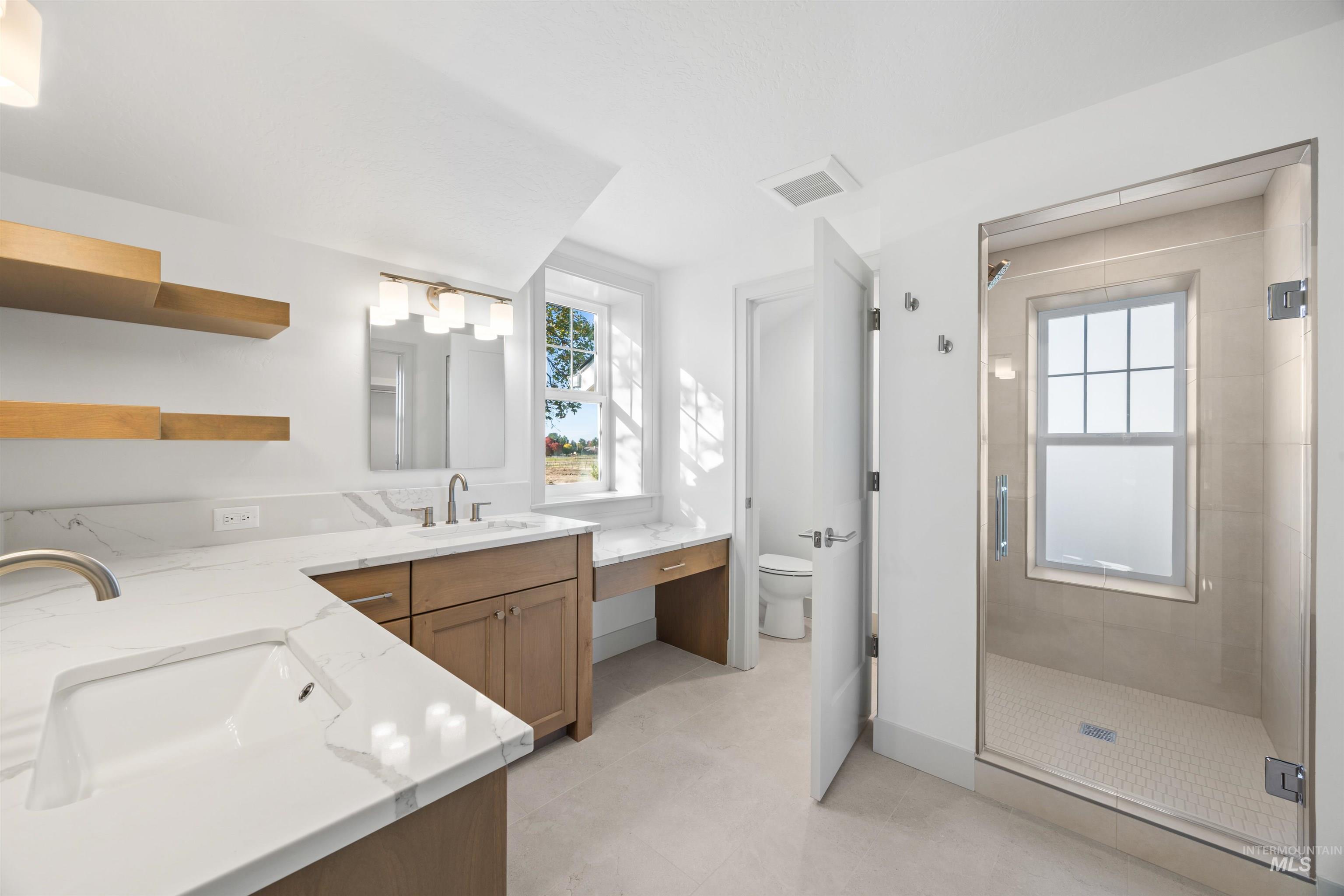 Bathroom featuring vanity, a stall shower, and light tile patterned floors