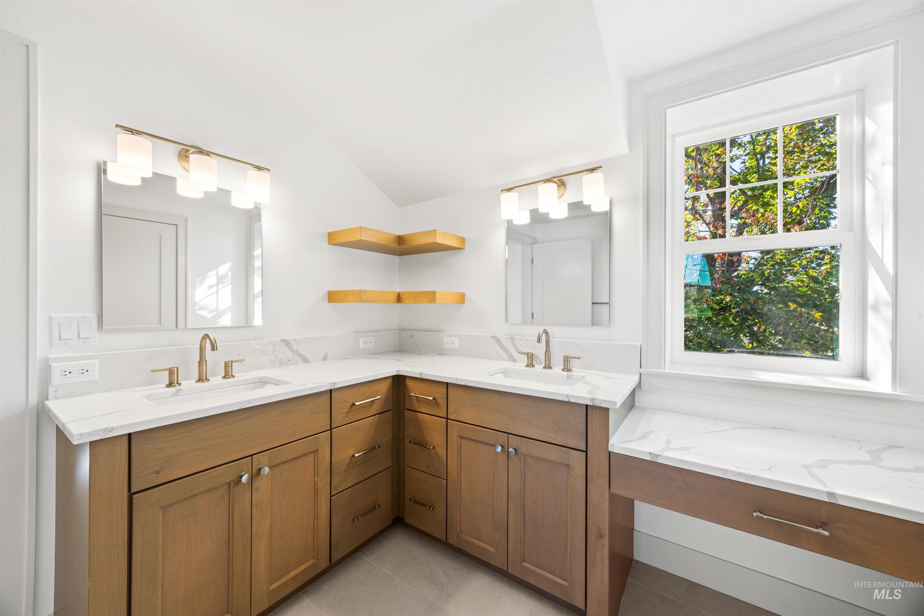 Full bathroom featuring healthy amount of natural light, double vanity, and light tile patterned floors